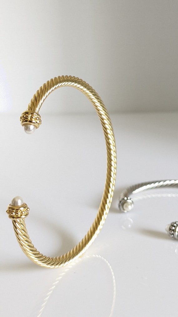 Elegant Gold Pearl Bangle Bracelet with twisted cable design and synthetic pearl accent, showcasing its adjustable fit and stylish appearance.