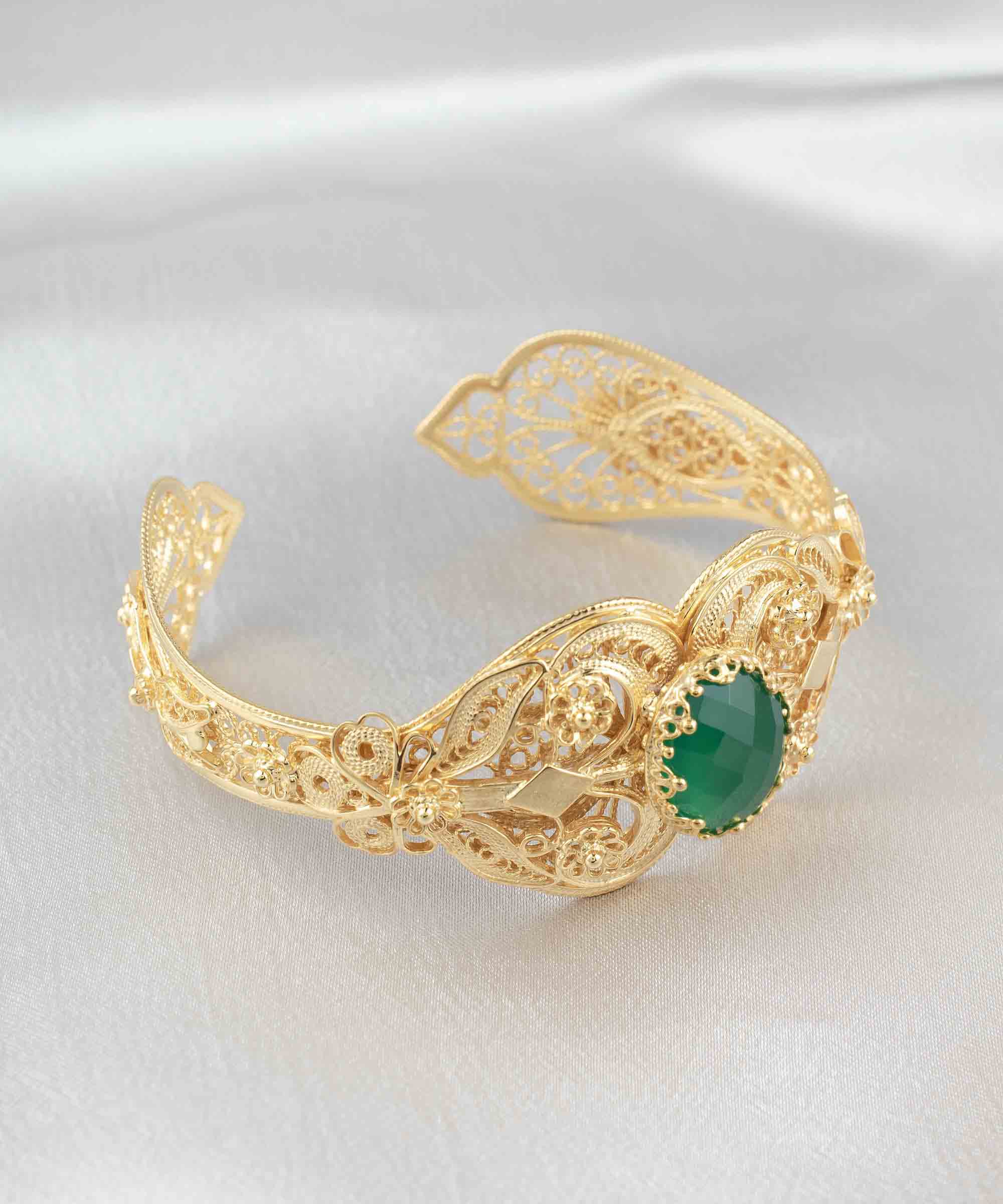 Gold plated sterling silver cuff bracelet featuring intricate filigree art and a double-sided faceted green agate gemstone.