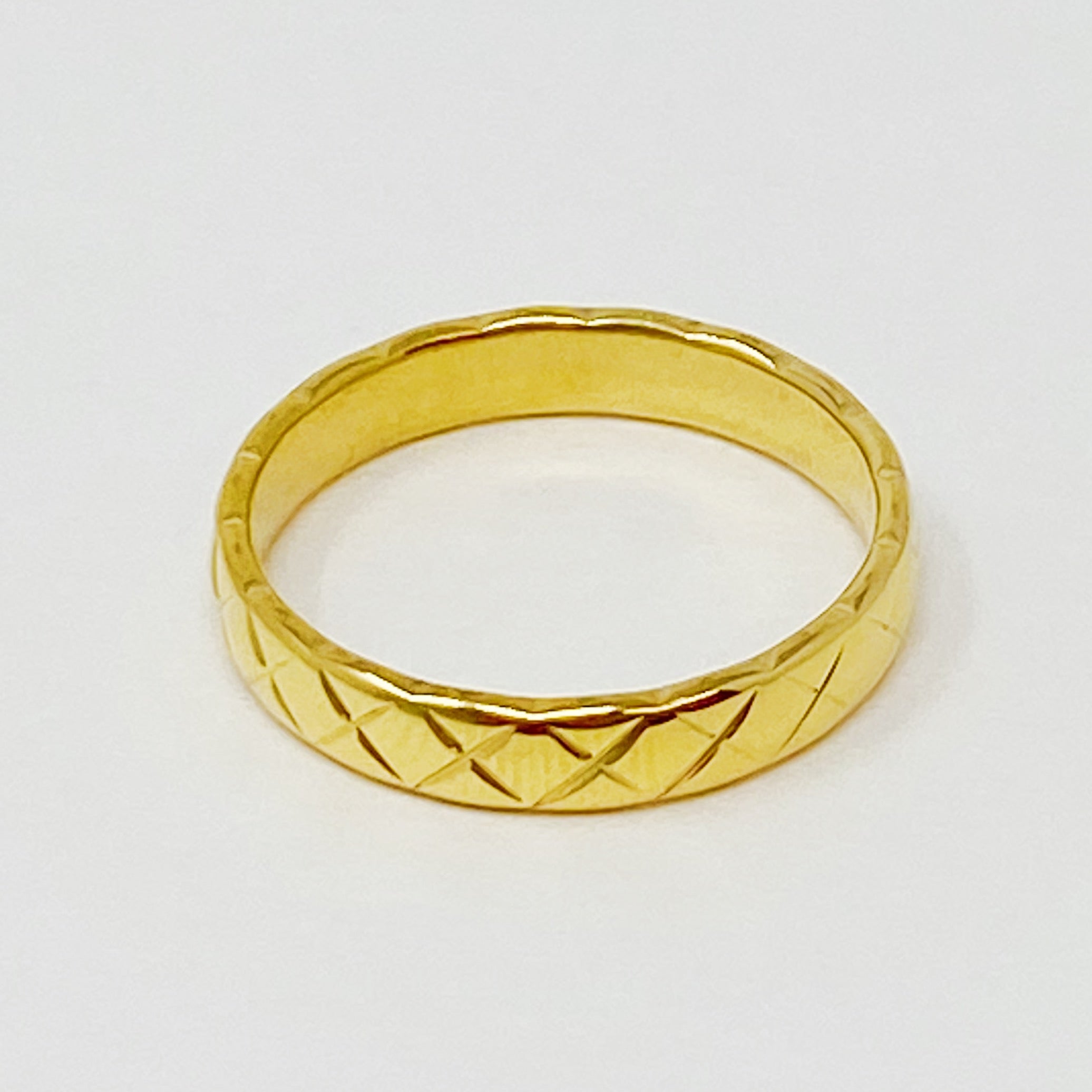 A stylish gold quilted ring made of stainless steel, featuring a textured surface, perfect for layering or wearing alone.