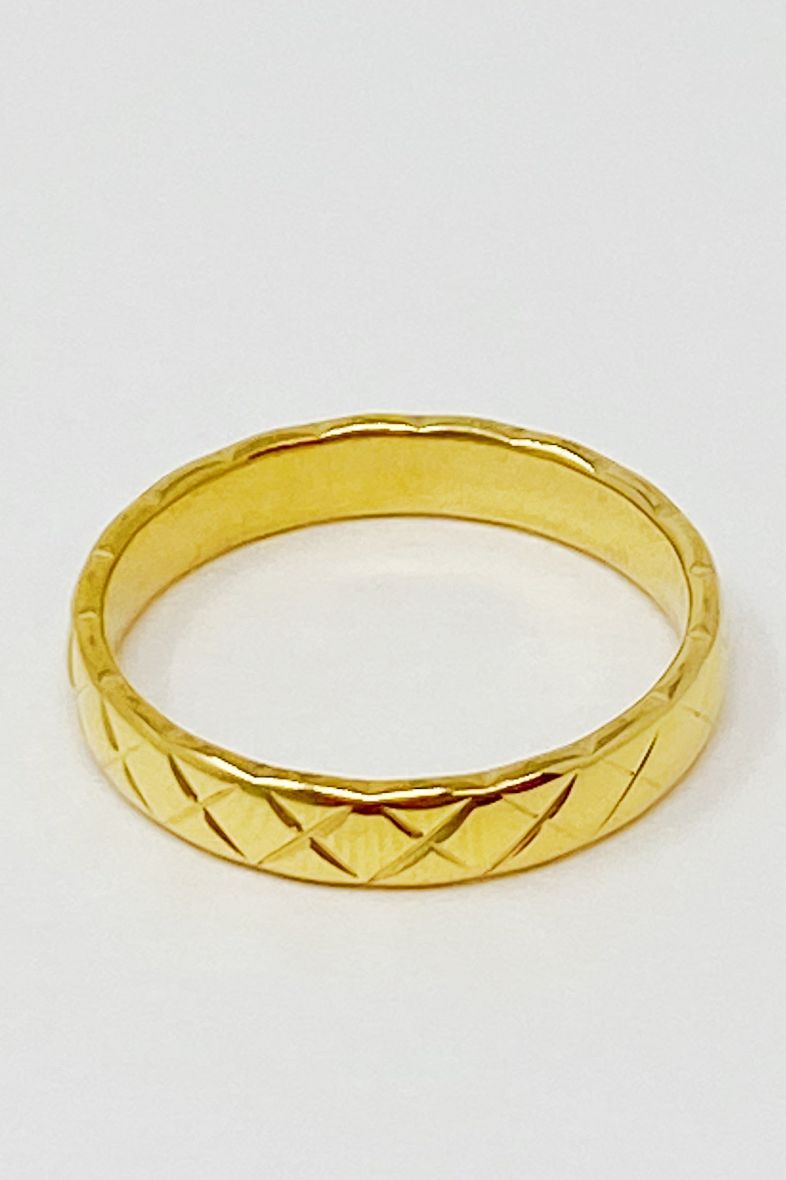 A stylish gold quilted ring made of stainless steel, featuring a textured surface, perfect for layering or wearing alone.