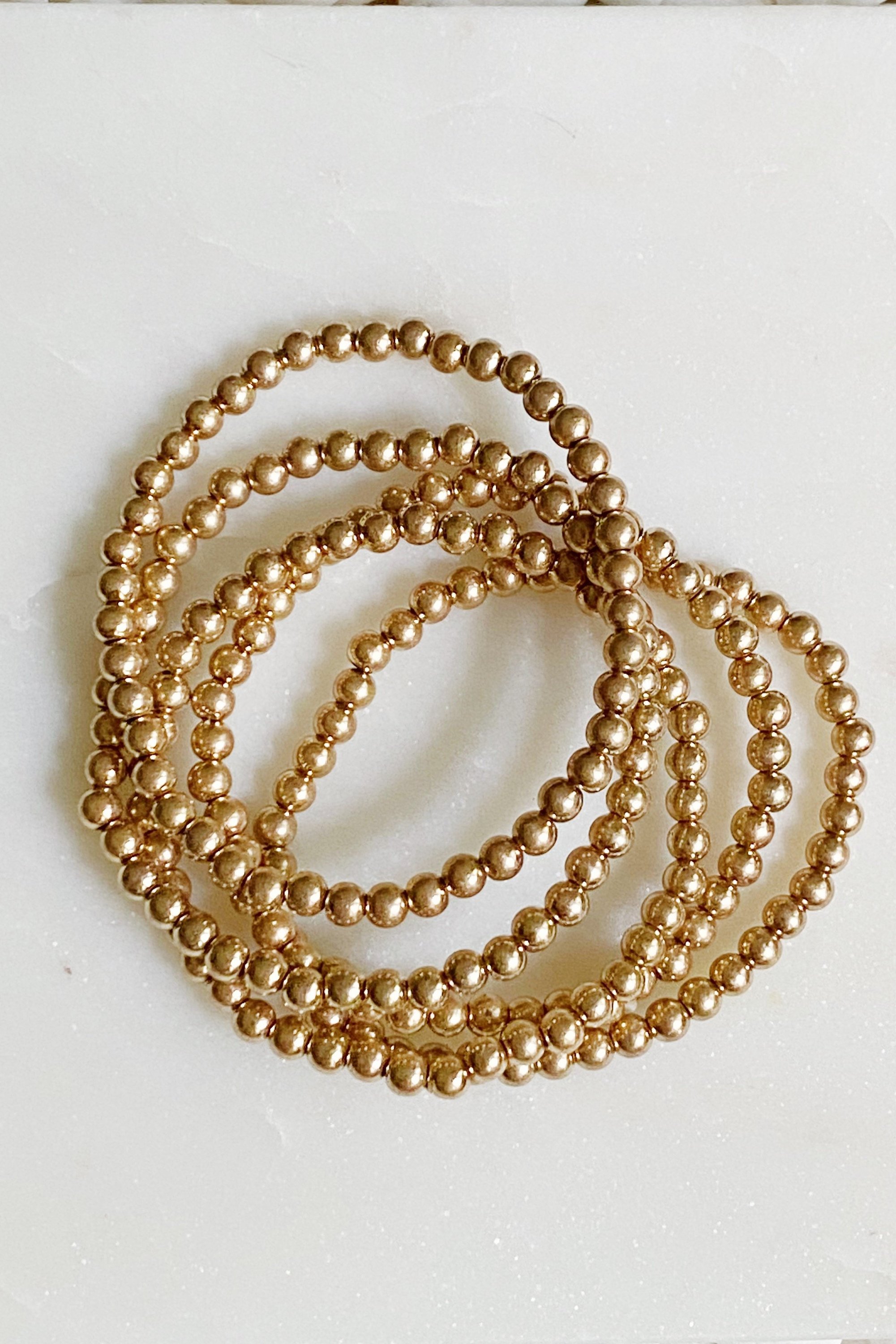 Golden Beads Bracelet Set featuring five strands of lightweight metal ball beads with a worn gold finish.