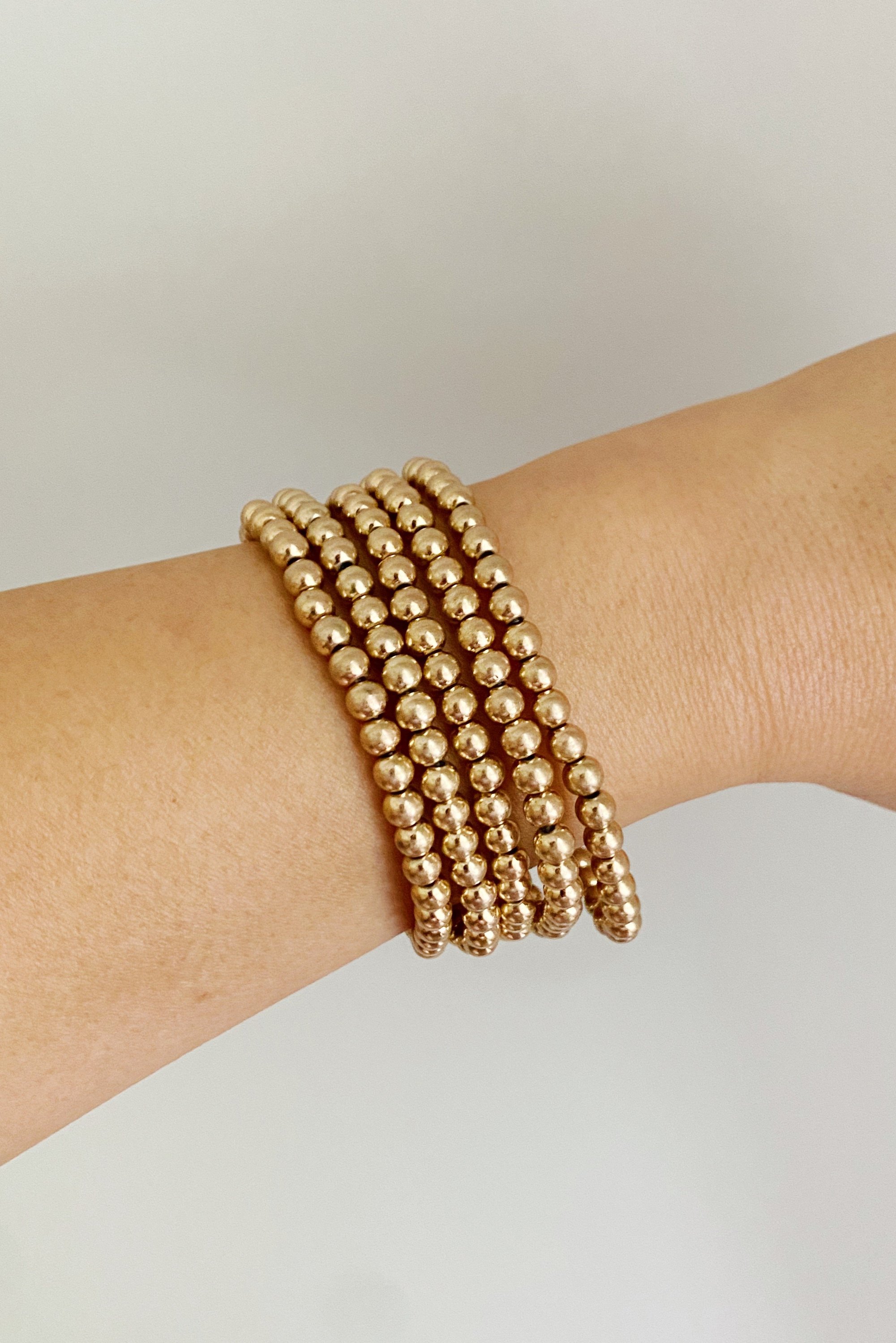 Golden Beads Bracelet Set featuring five strands of lightweight metal ball beads with a worn gold finish.