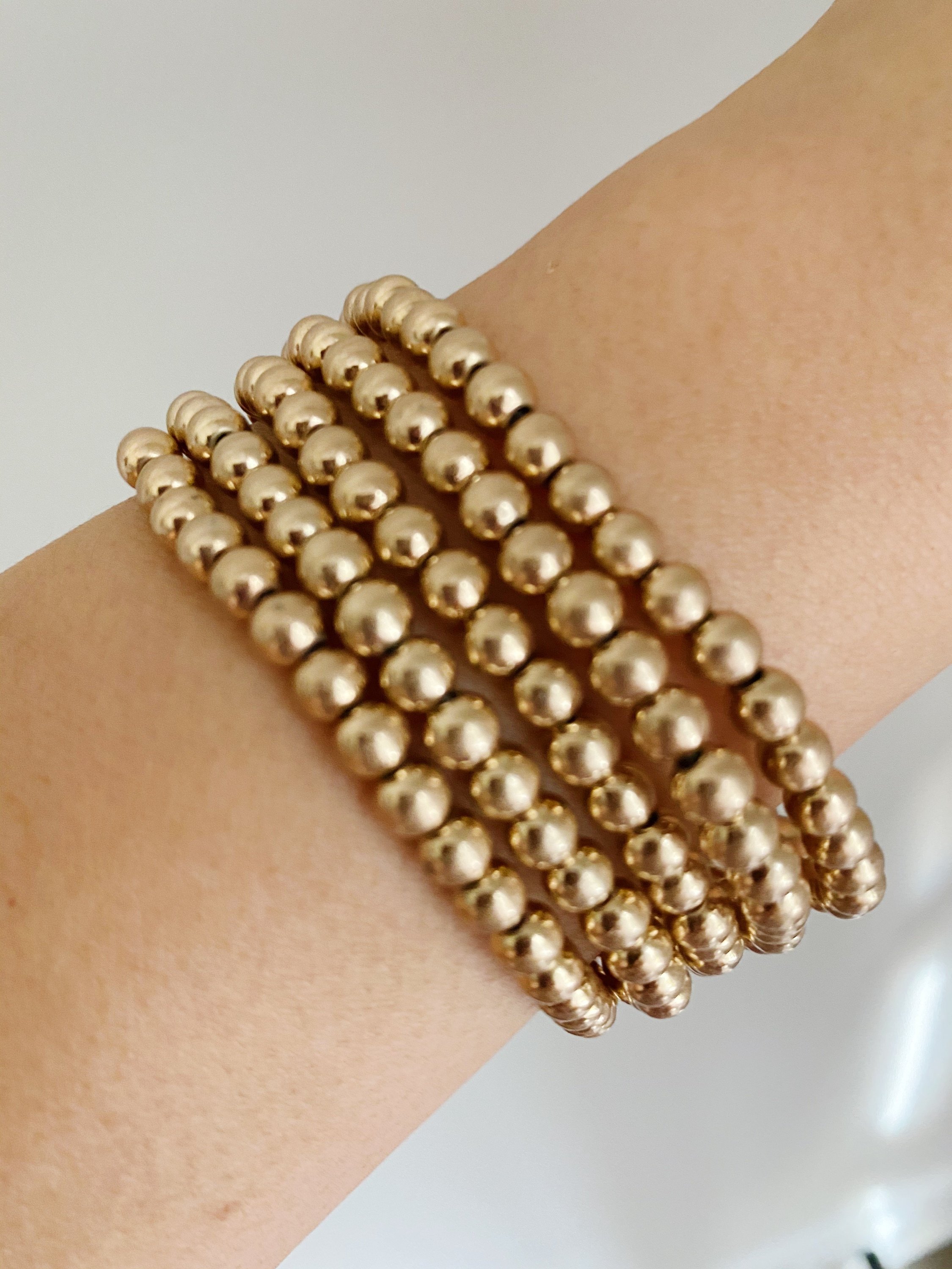 Golden Beads Bracelet Set featuring five strands of lightweight metal ball beads with a worn gold finish.