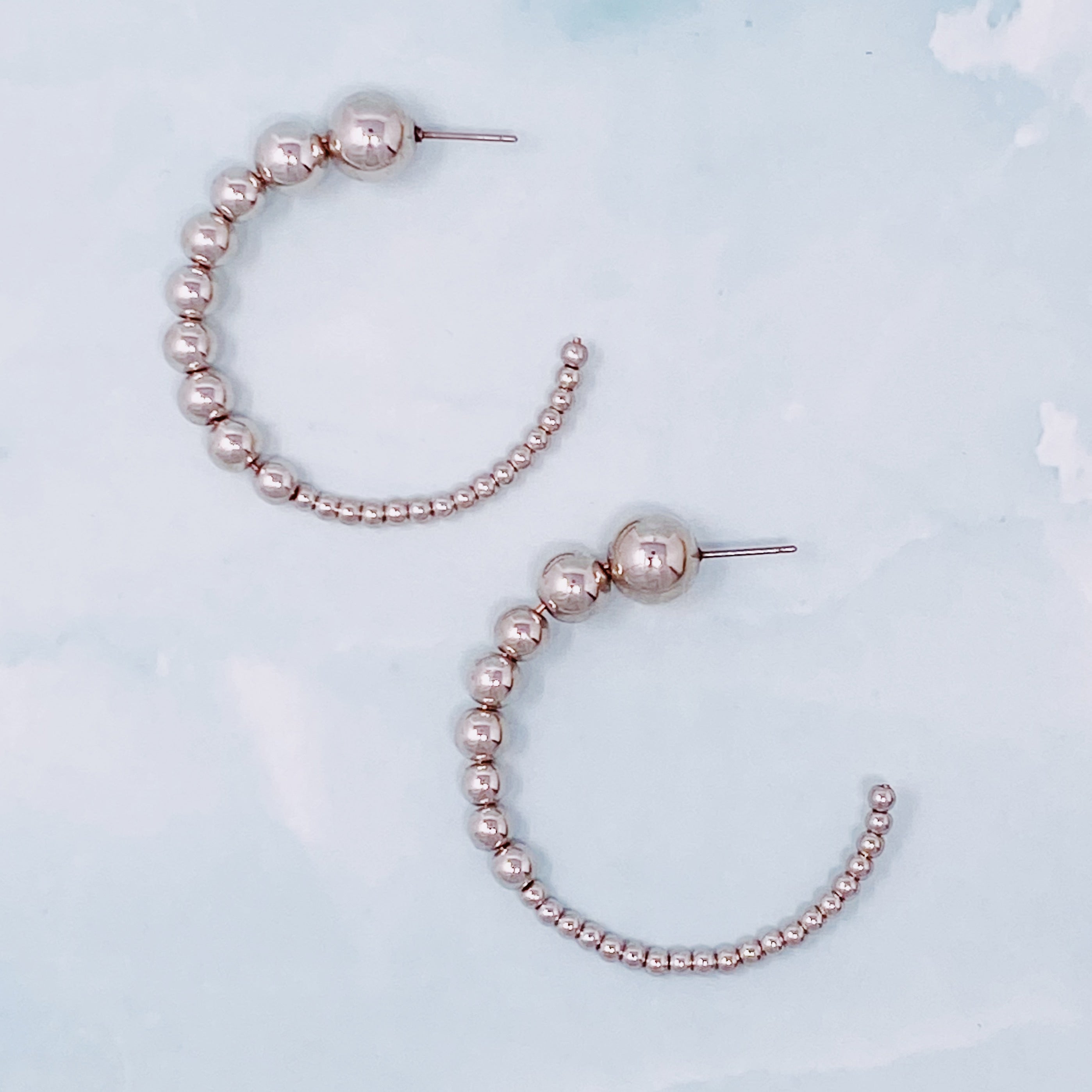 Stylish Gradation Bauble Hoop Earrings featuring a unique arrangement of large and small beads in a hoop design.