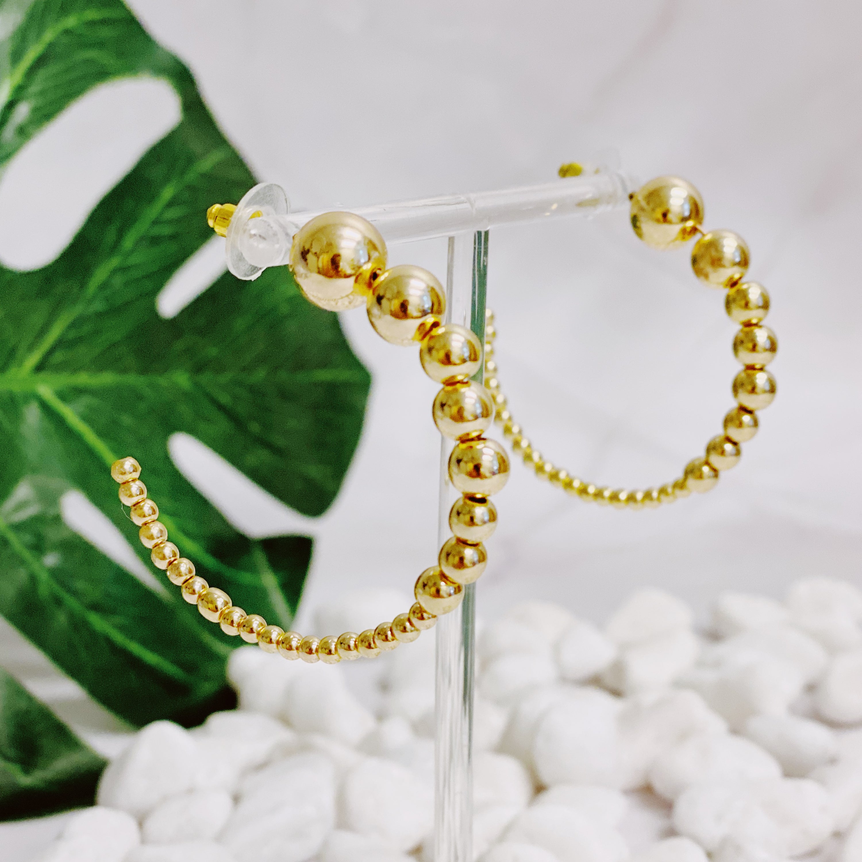 Stylish Gradation Bauble Hoop Earrings featuring a unique arrangement of large and small beads in a hoop design.