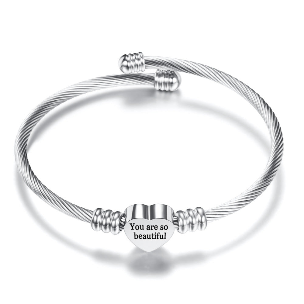 A high-polished stainless steel charm bangle featuring a heart initial charm and the quote 'You are so Beautiful', designed for comfort and elegance.