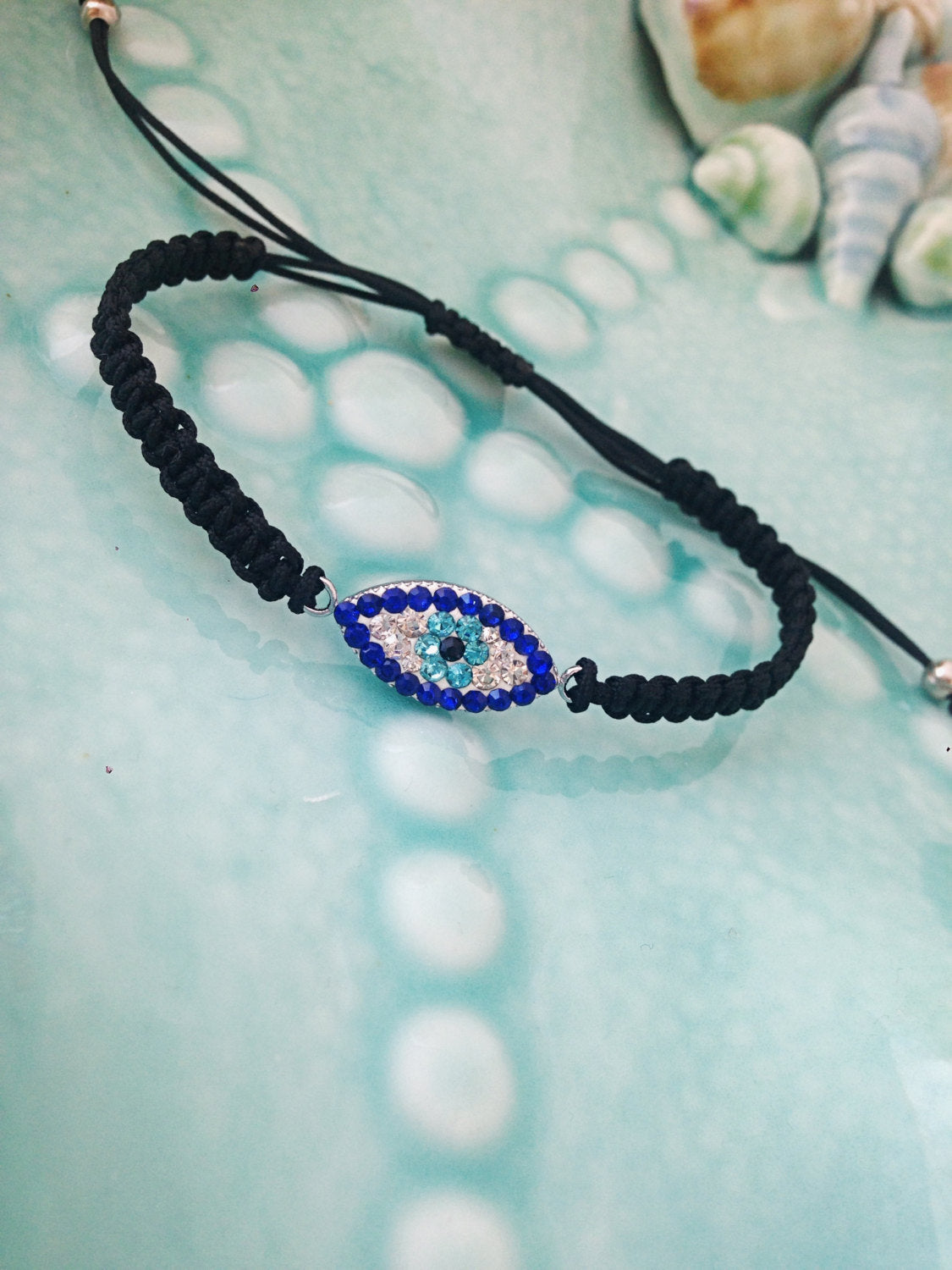 Handmade Greek Evil Eye Bracelet featuring an adjustable black macramé string and traditional evil eye charm, symbolizing protection and good luck.