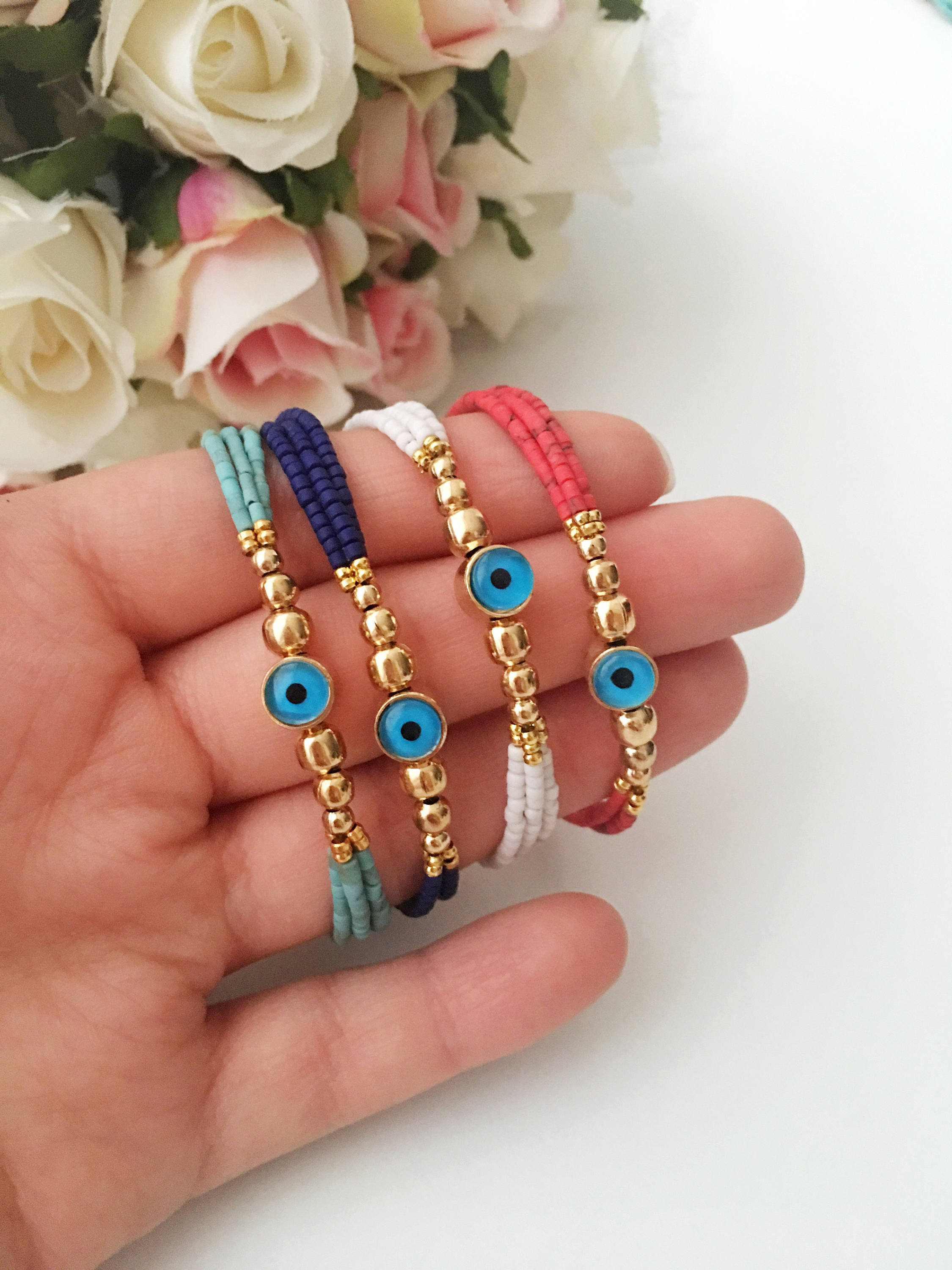 Handmade Greek Evil Eye Bracelet featuring vibrant seed beads and gold accents, available in turquoise, dark blue, red, and white.