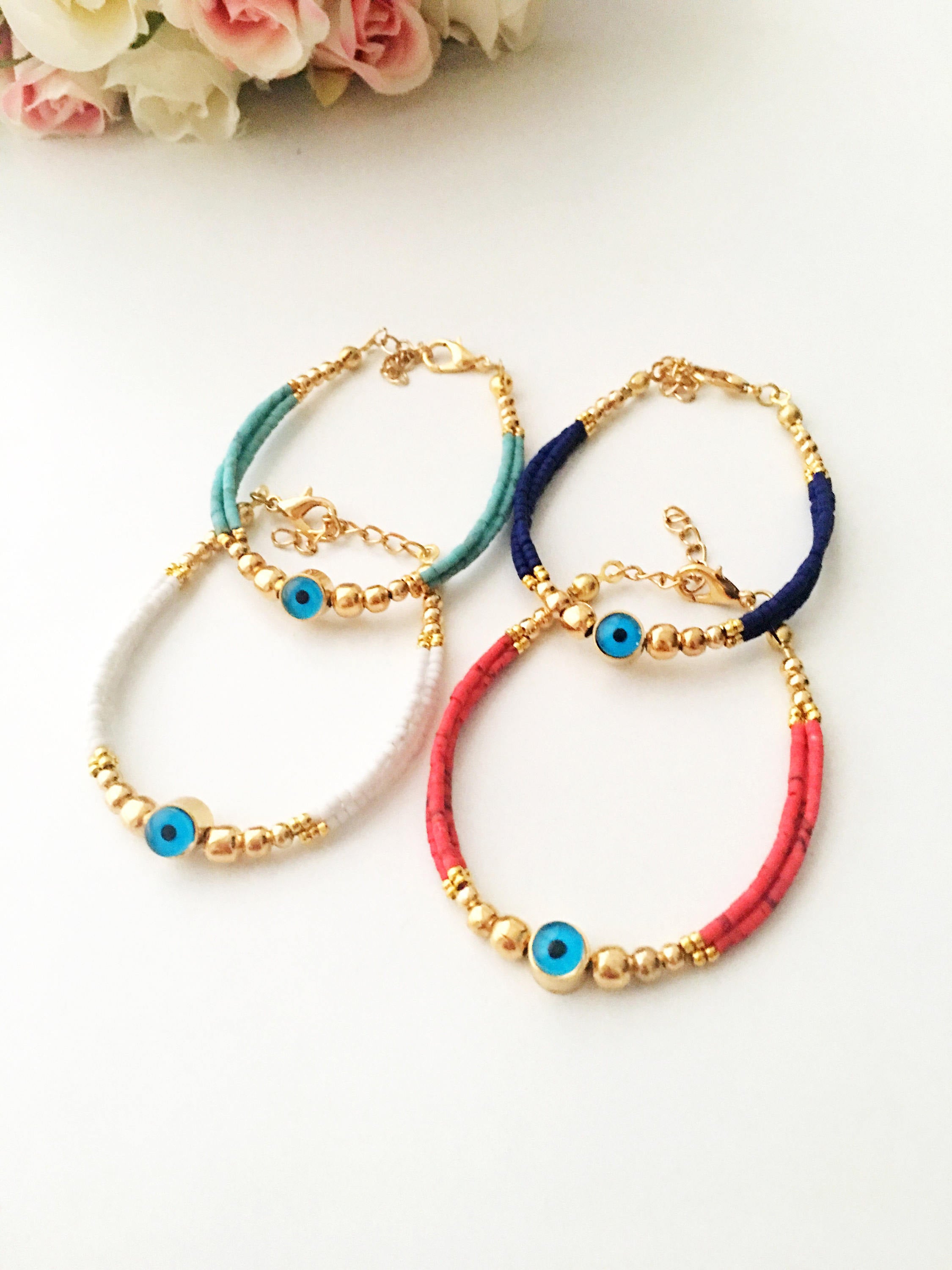 Handmade Greek Evil Eye Bracelet featuring vibrant seed beads and gold accents, available in turquoise, dark blue, red, and white.