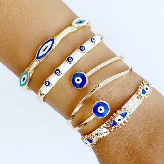 A beautiful Greek Evil Eye Cuff Bracelet featuring a blue evil eye design on a gold adjustable cuff, symbolizing protection and good luck.