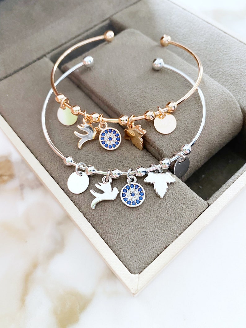 A stunning Greek Evil Eye Cuff Bracelet featuring a silver and rose finish, adorned with an evil eye charm for protection.