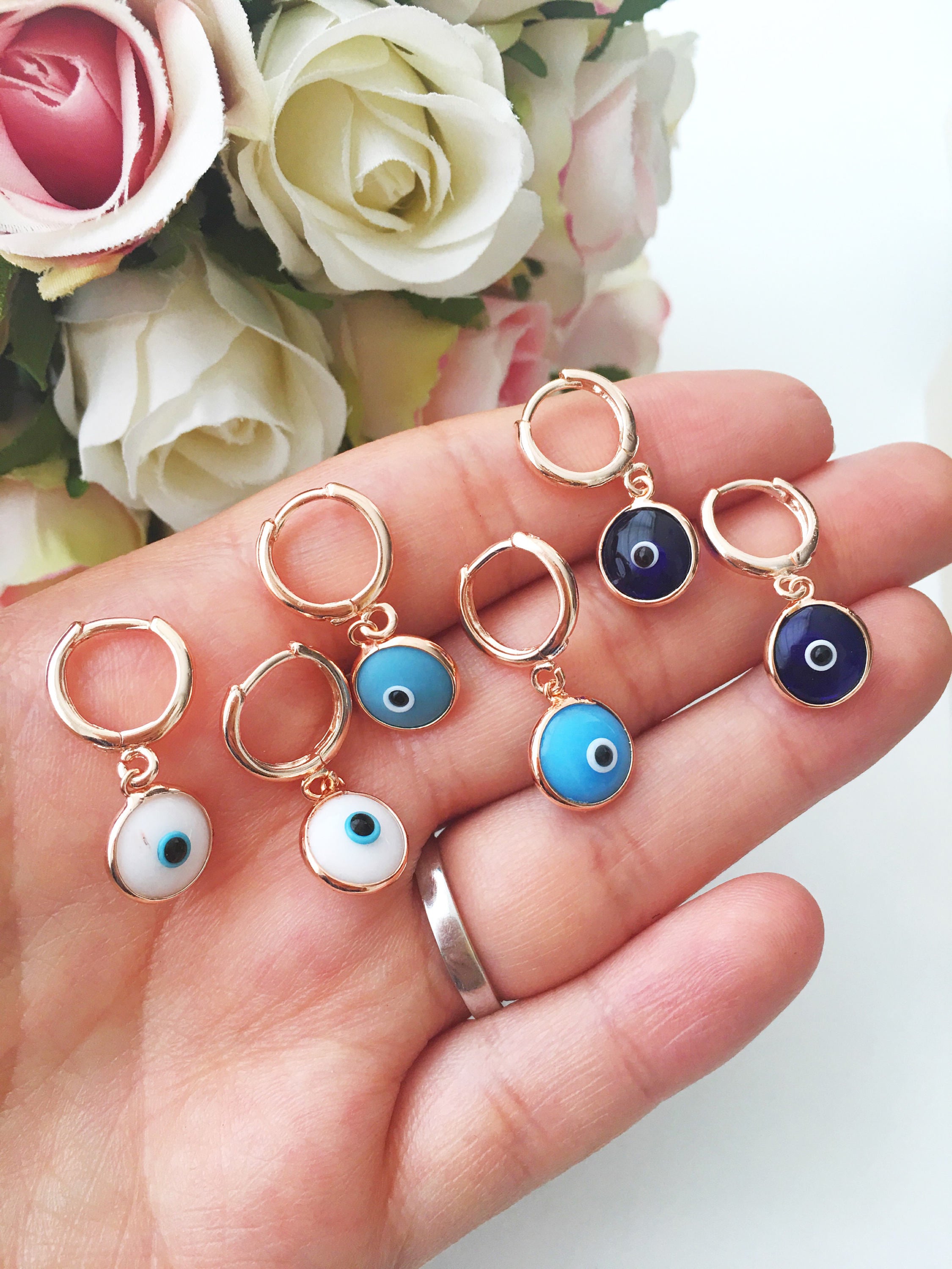 Hand holding evil eye earrings.