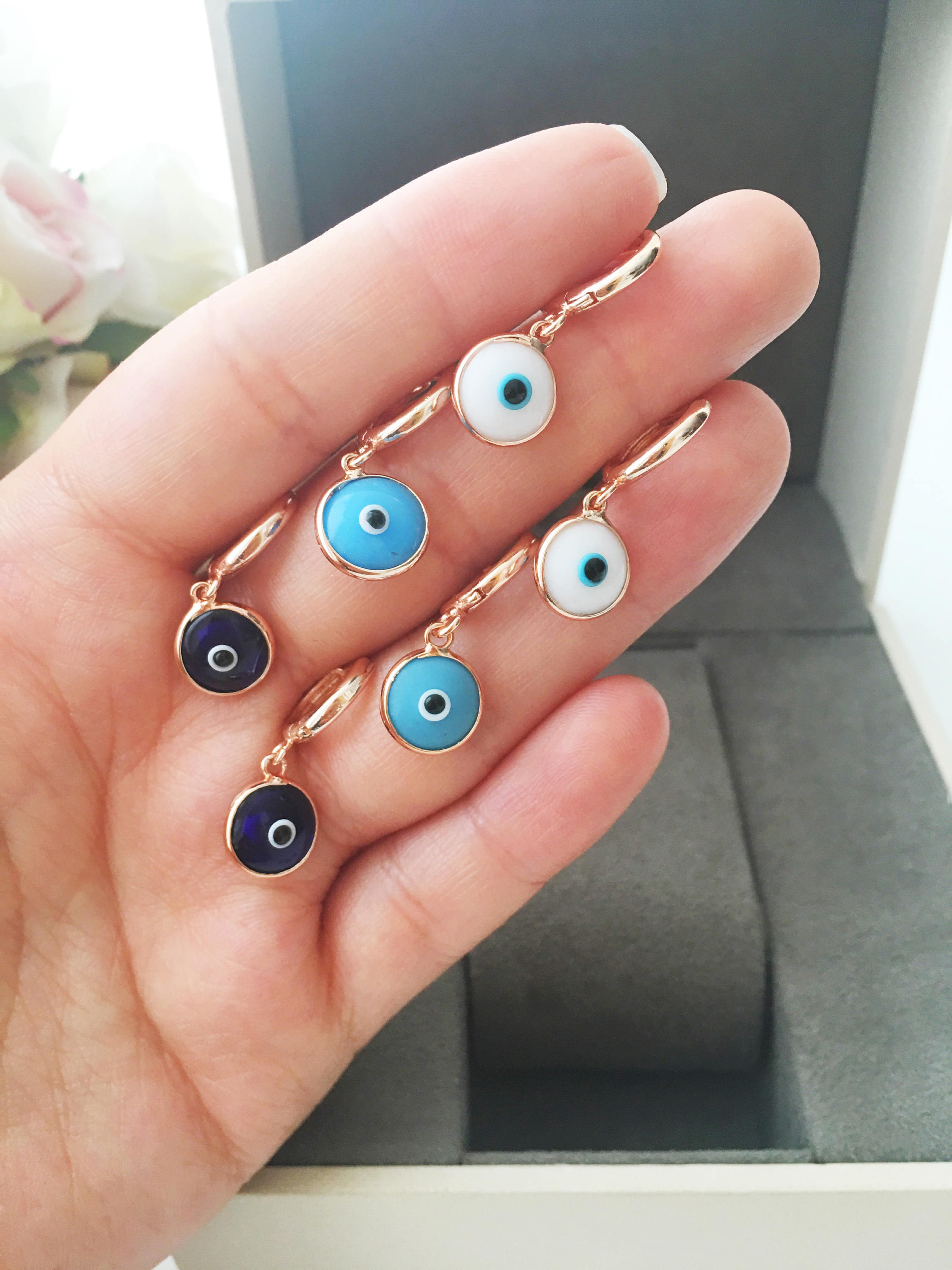 Hand holding colorful evil eye charms.