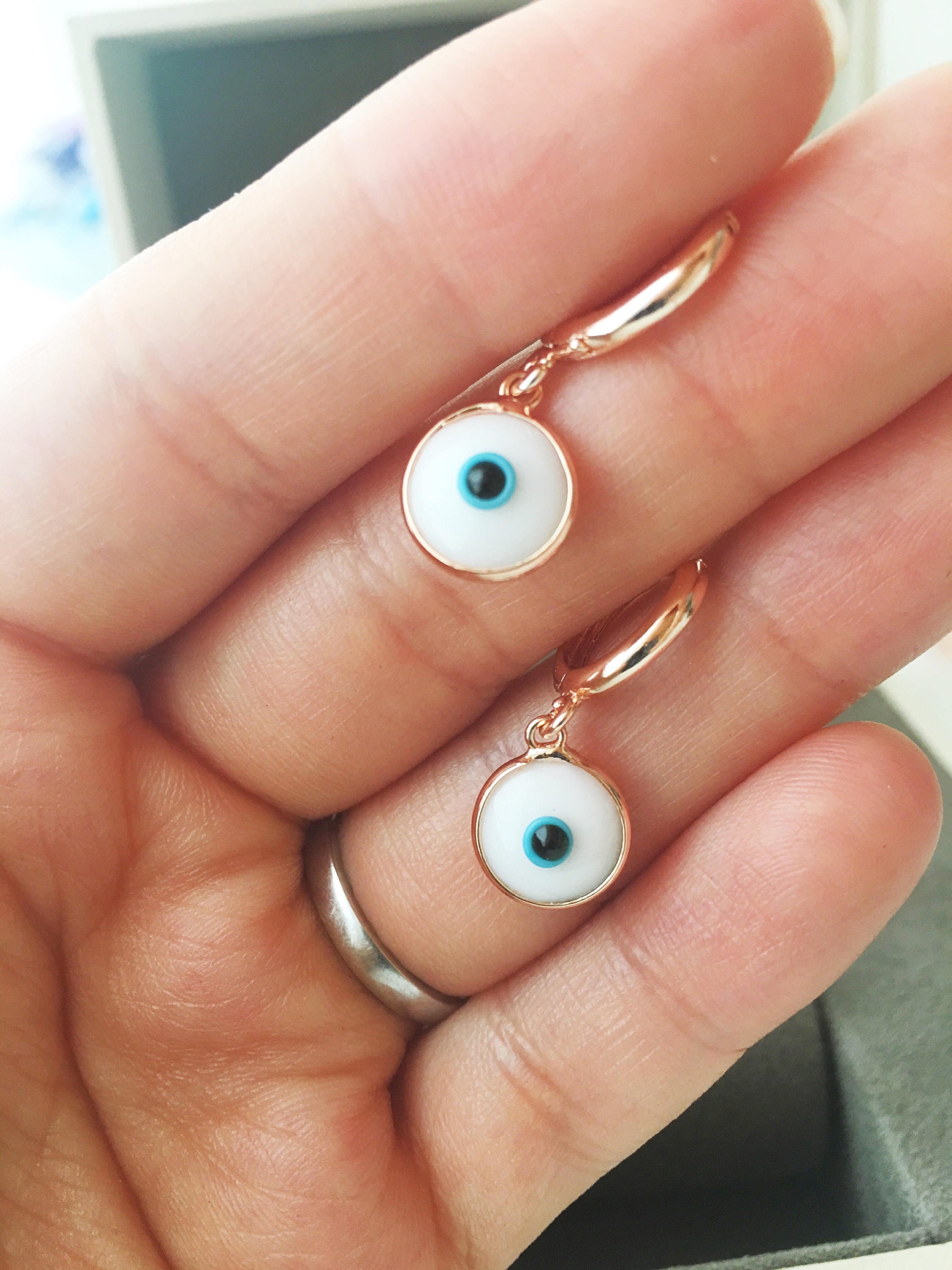 A pair of handmade Greek Evil Eye Hoop Earrings featuring blue and turquoise evil eye charms on gold hoops.