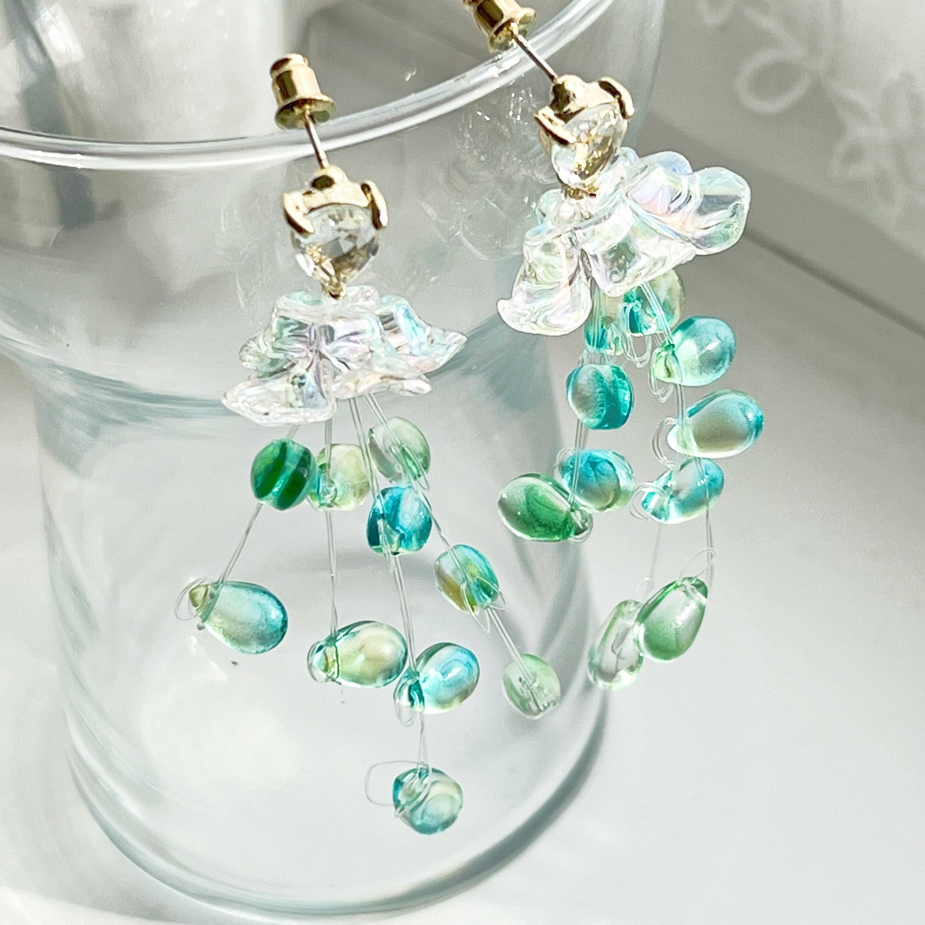 Elegant green drop earrings with crystal flower design, showcasing a stylish string-of-pearls look.