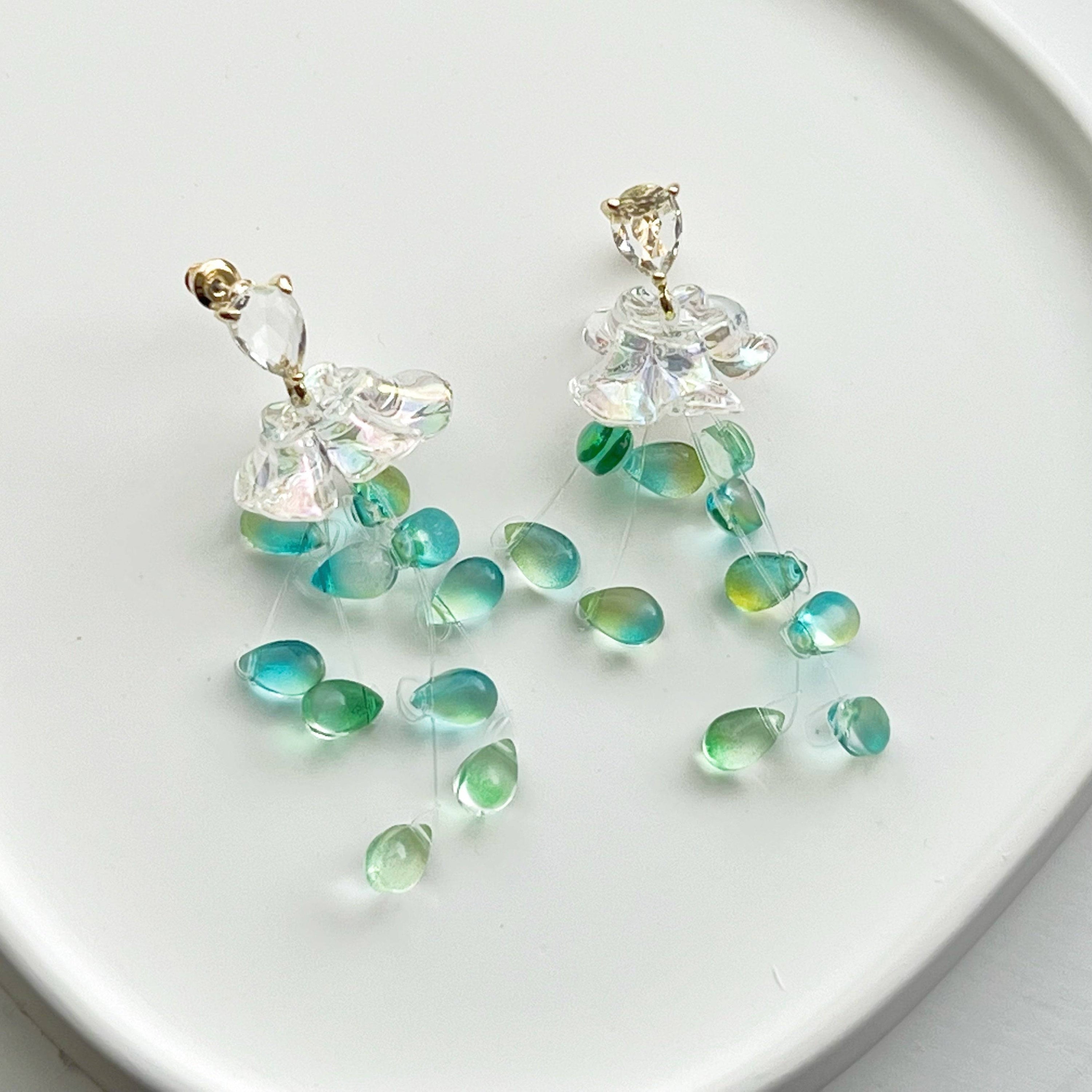 Elegant green drop earrings with crystal flower design, showcasing a stylish string-of-pearls look.