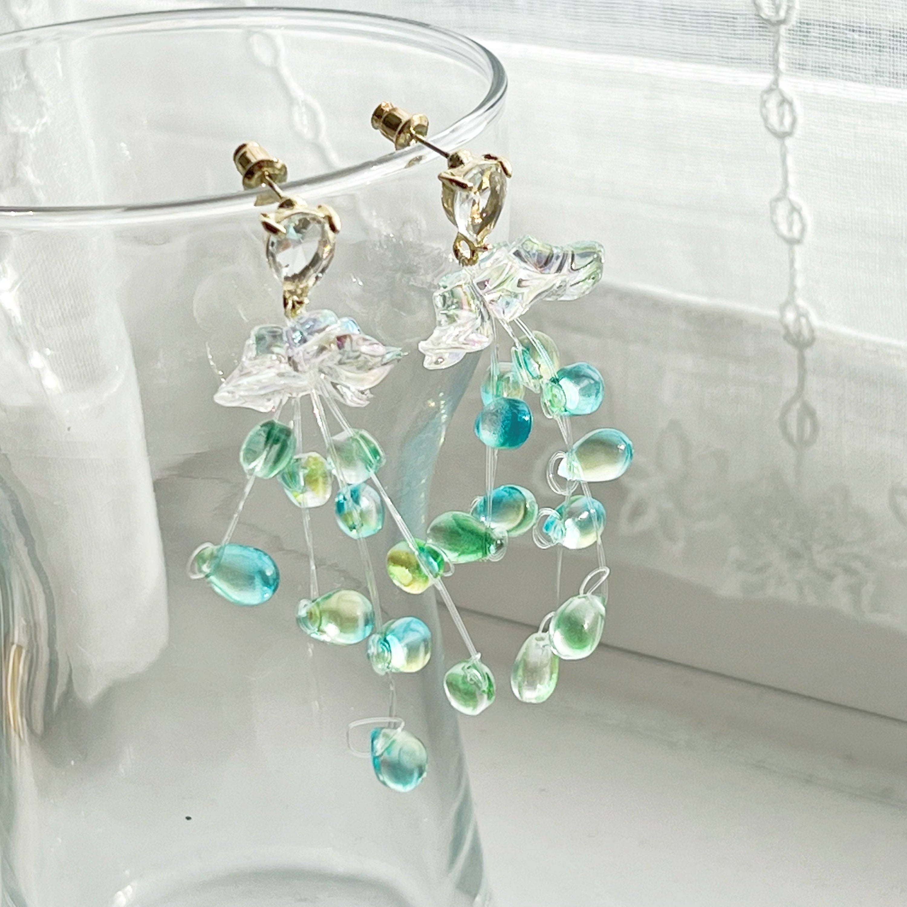 Elegant green drop earrings with crystal flower design, showcasing a stylish string-of-pearls look.