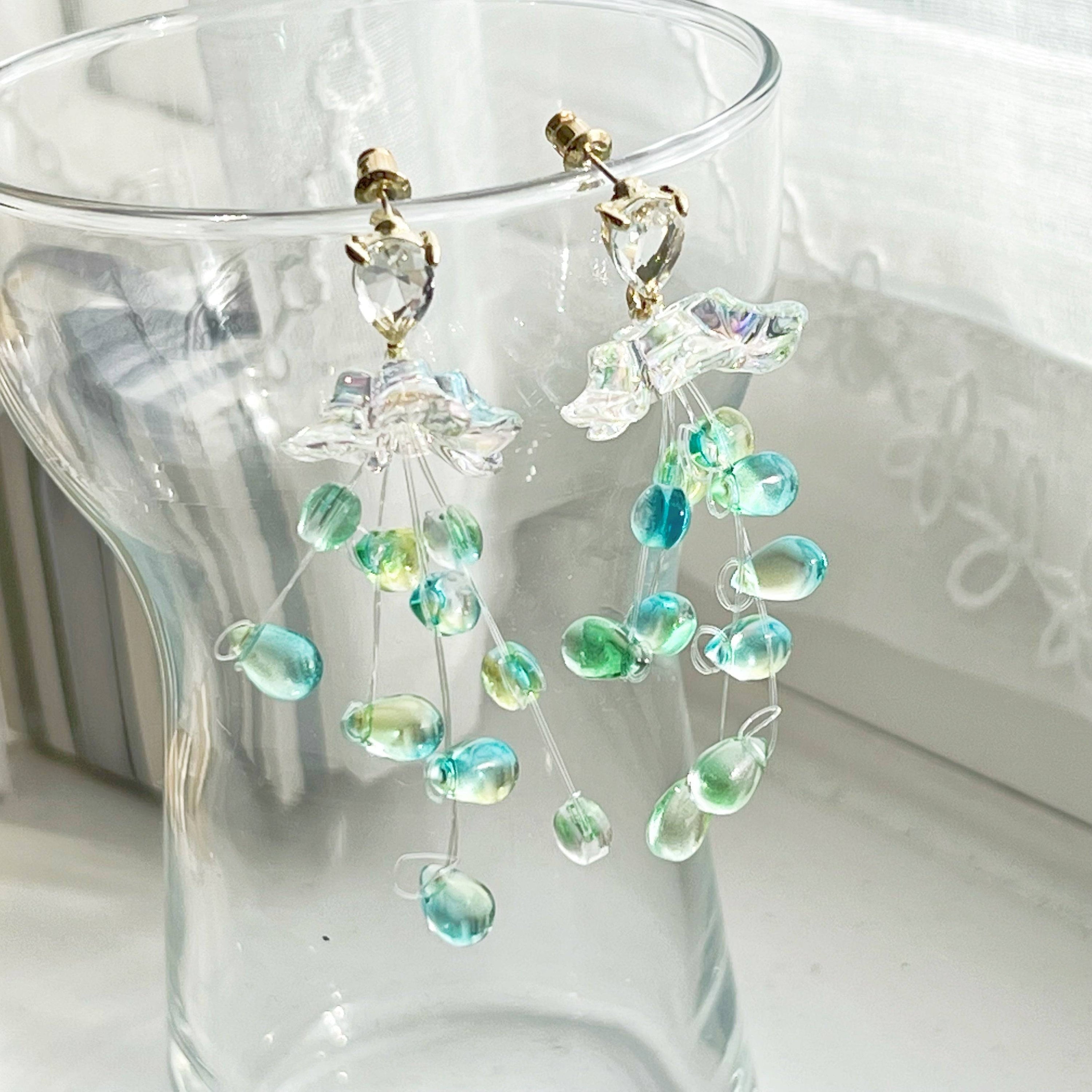 Elegant green drop earrings with crystal flower design, showcasing a stylish string-of-pearls look.