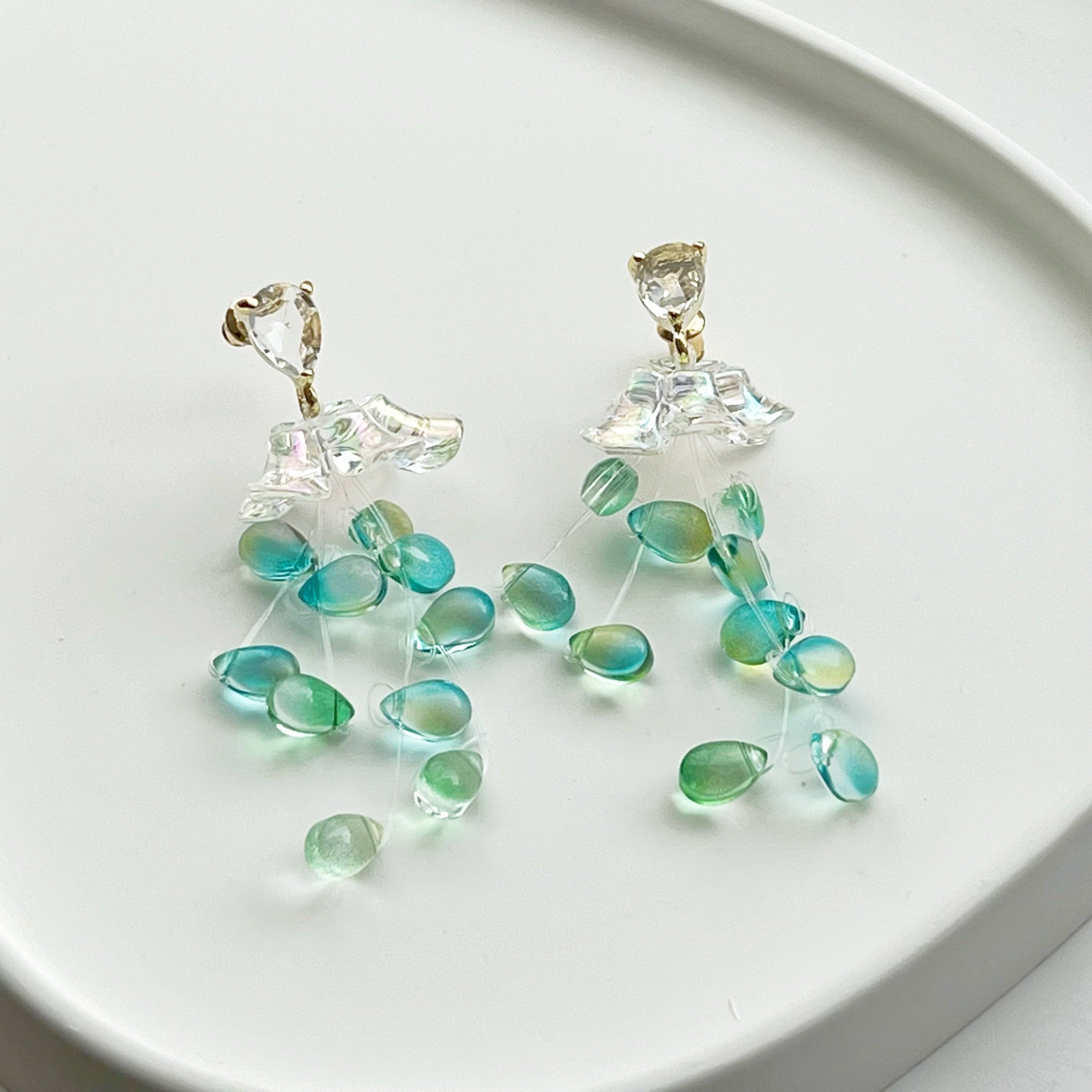 Elegant green drop earrings with crystal flower design, showcasing a stylish string-of-pearls look.