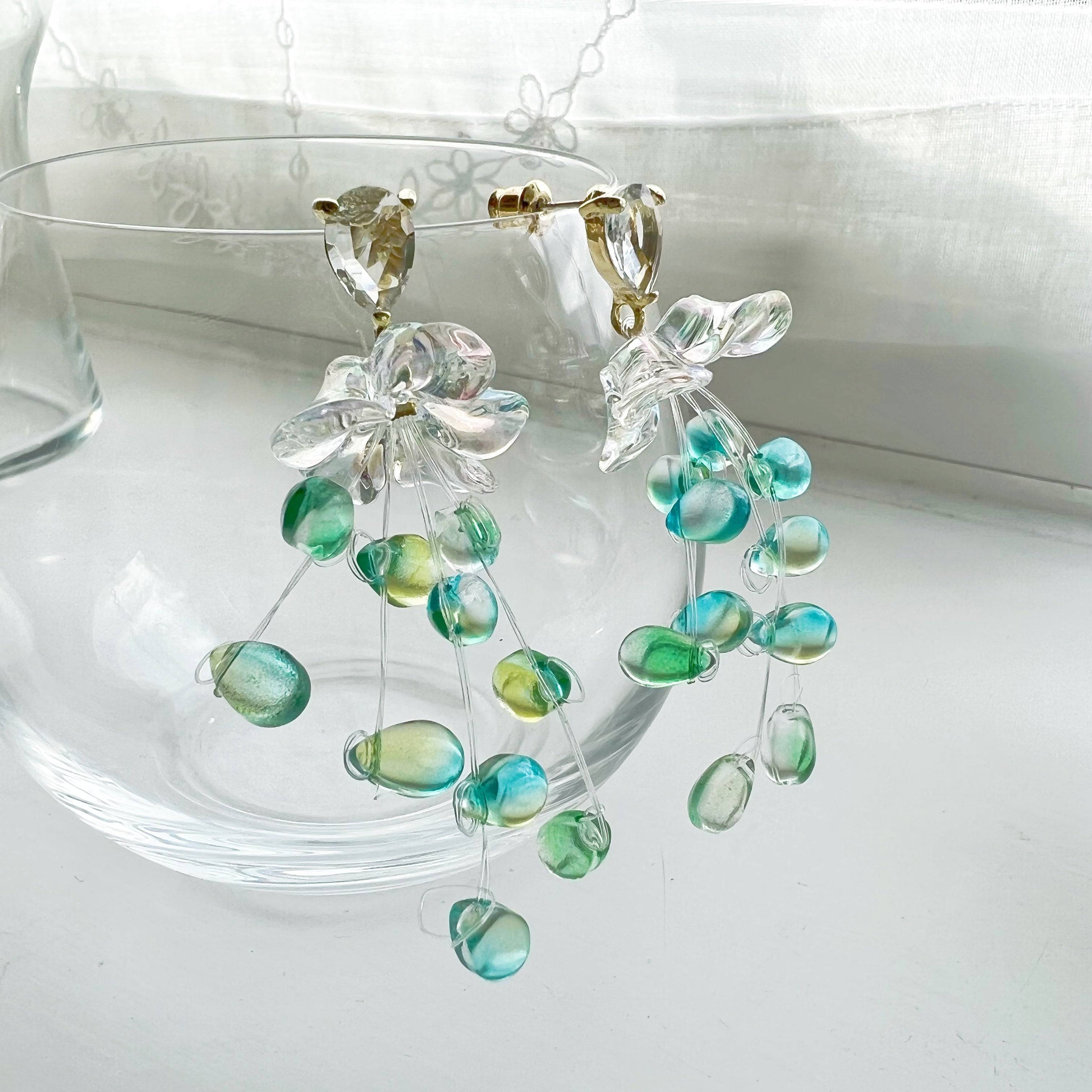 Elegant green drop earrings with crystal flower design, showcasing a stylish string-of-pearls look.