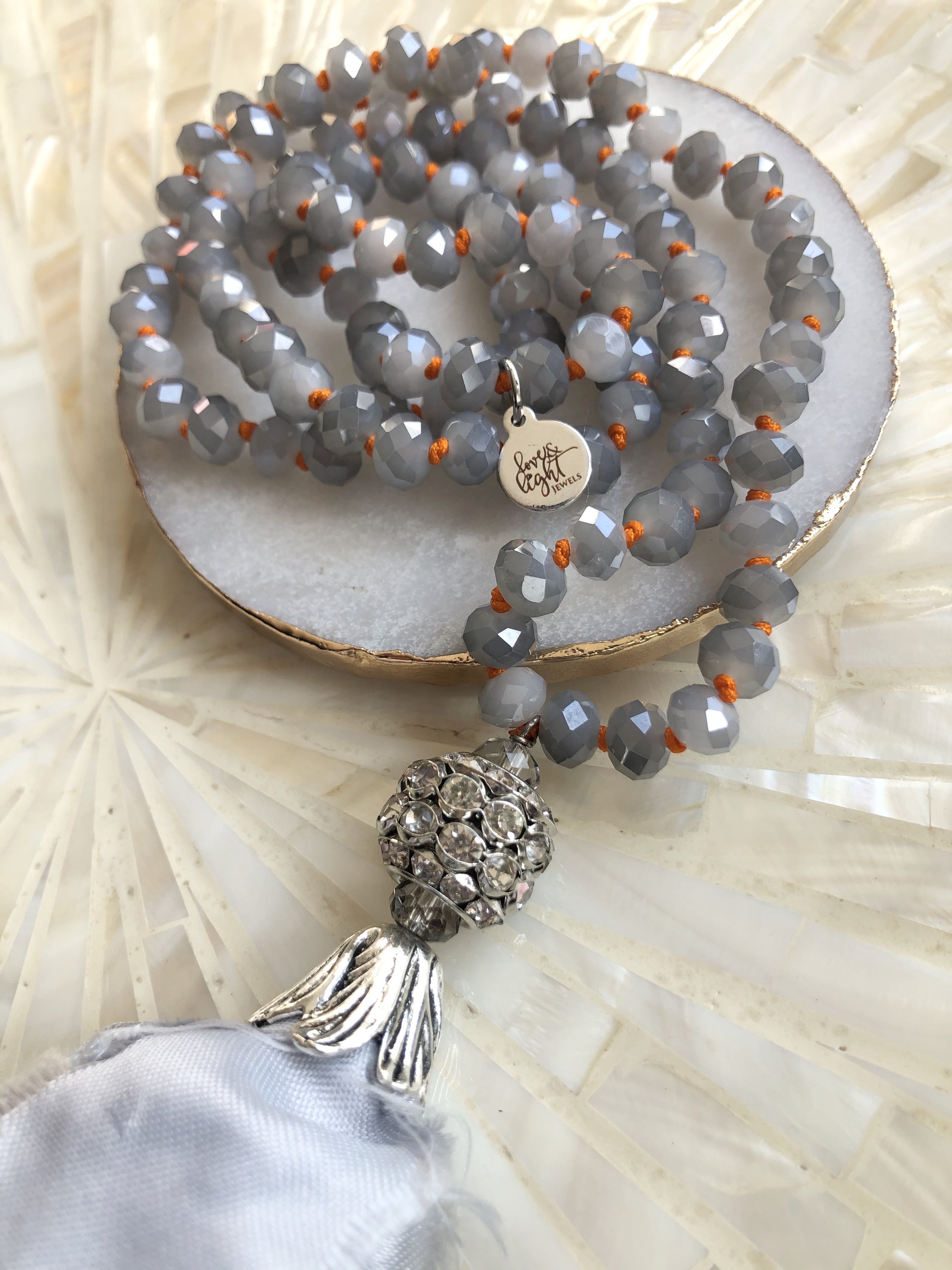 A stylish Grey Sari Tassel Necklace featuring grey crystal beads, a satin tassel, and a sparkling rhinestone encrusted pendant.