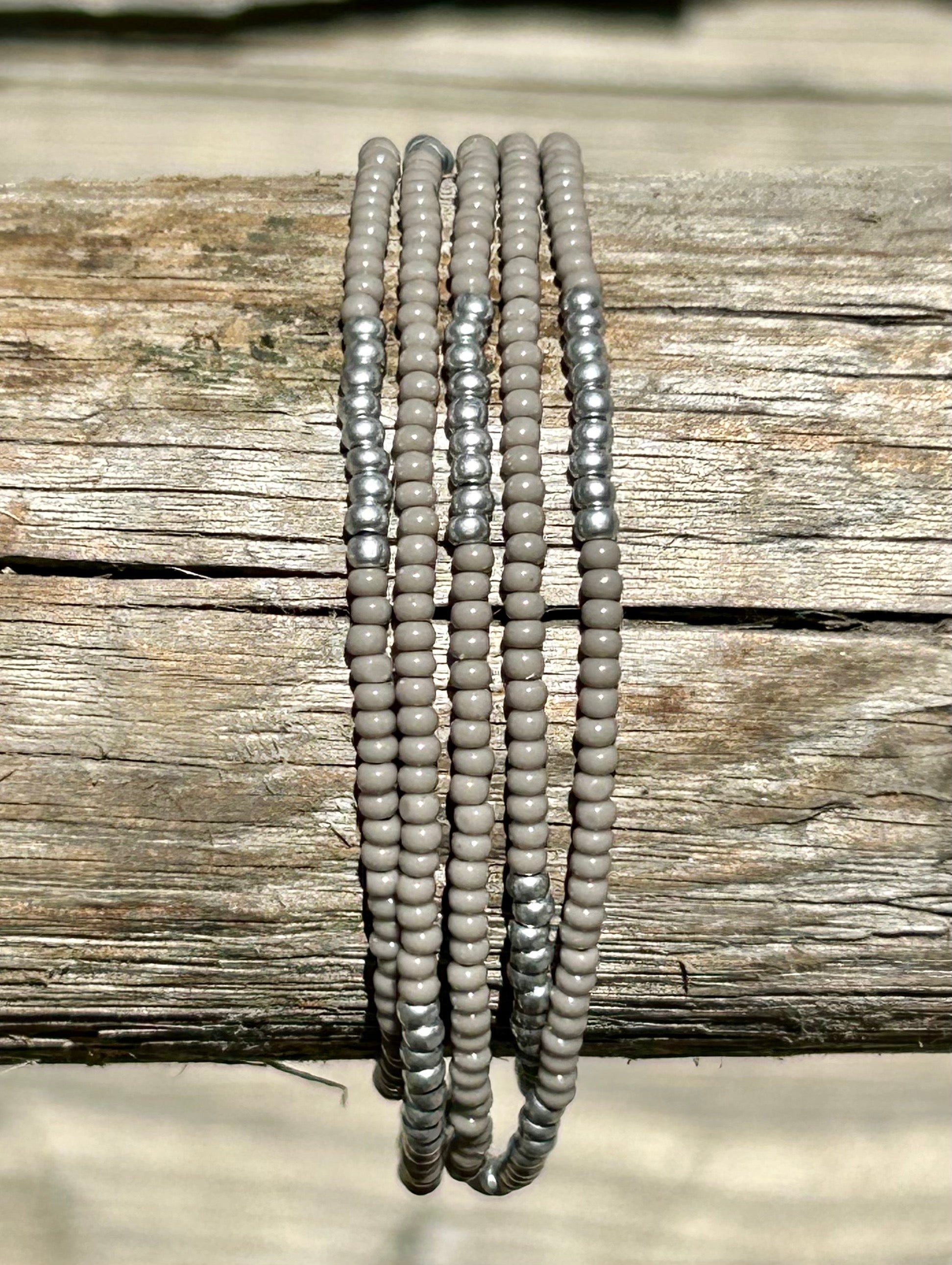 Grey and silver-striped beaded 5-wrap bracelet made with Czech glass seed beads on elastic cording, showcasing an elegant design.