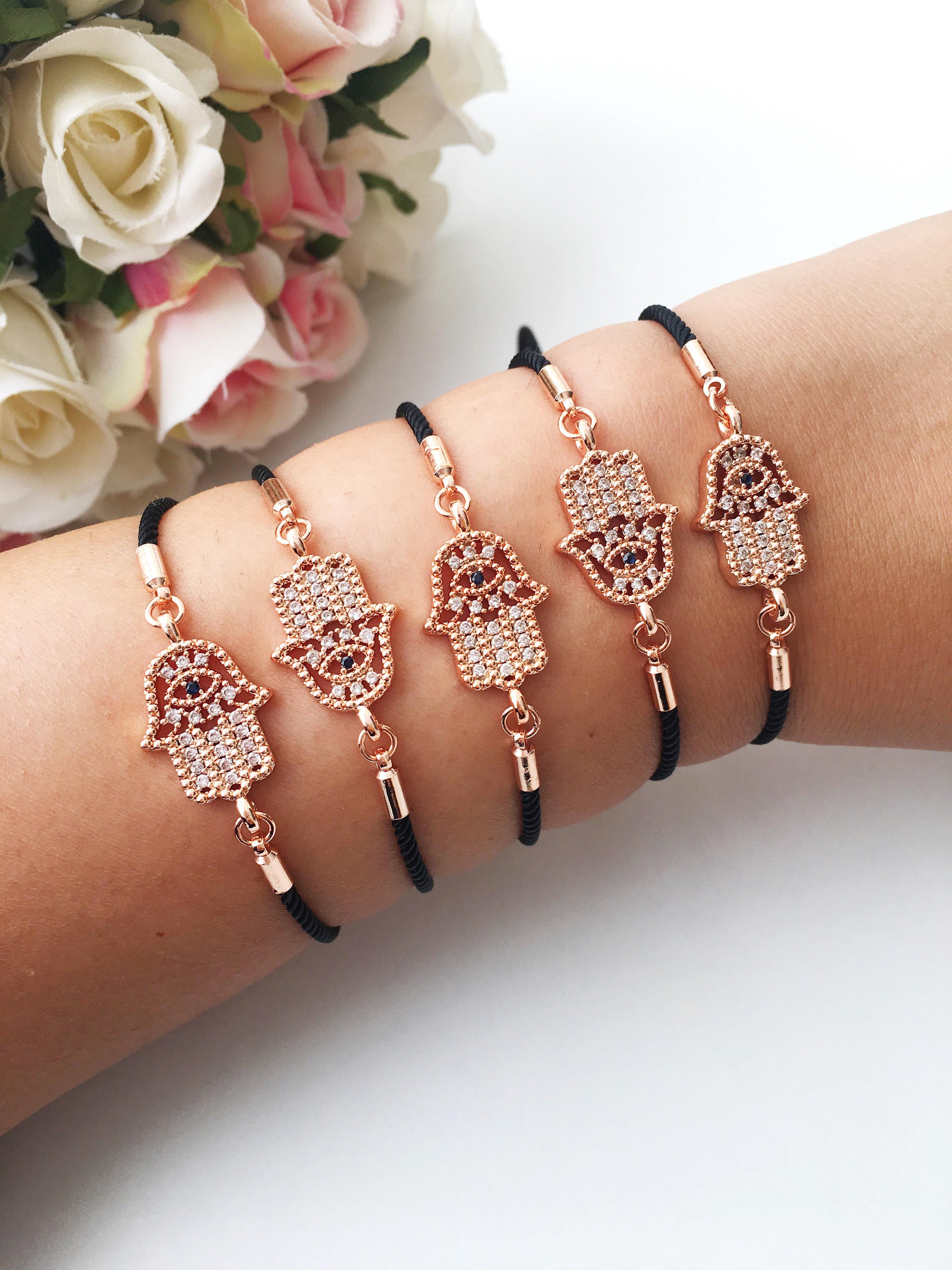 Handmade Hamsa charm bracelet featuring a rose gold zirconia charm on a black adjustable string.