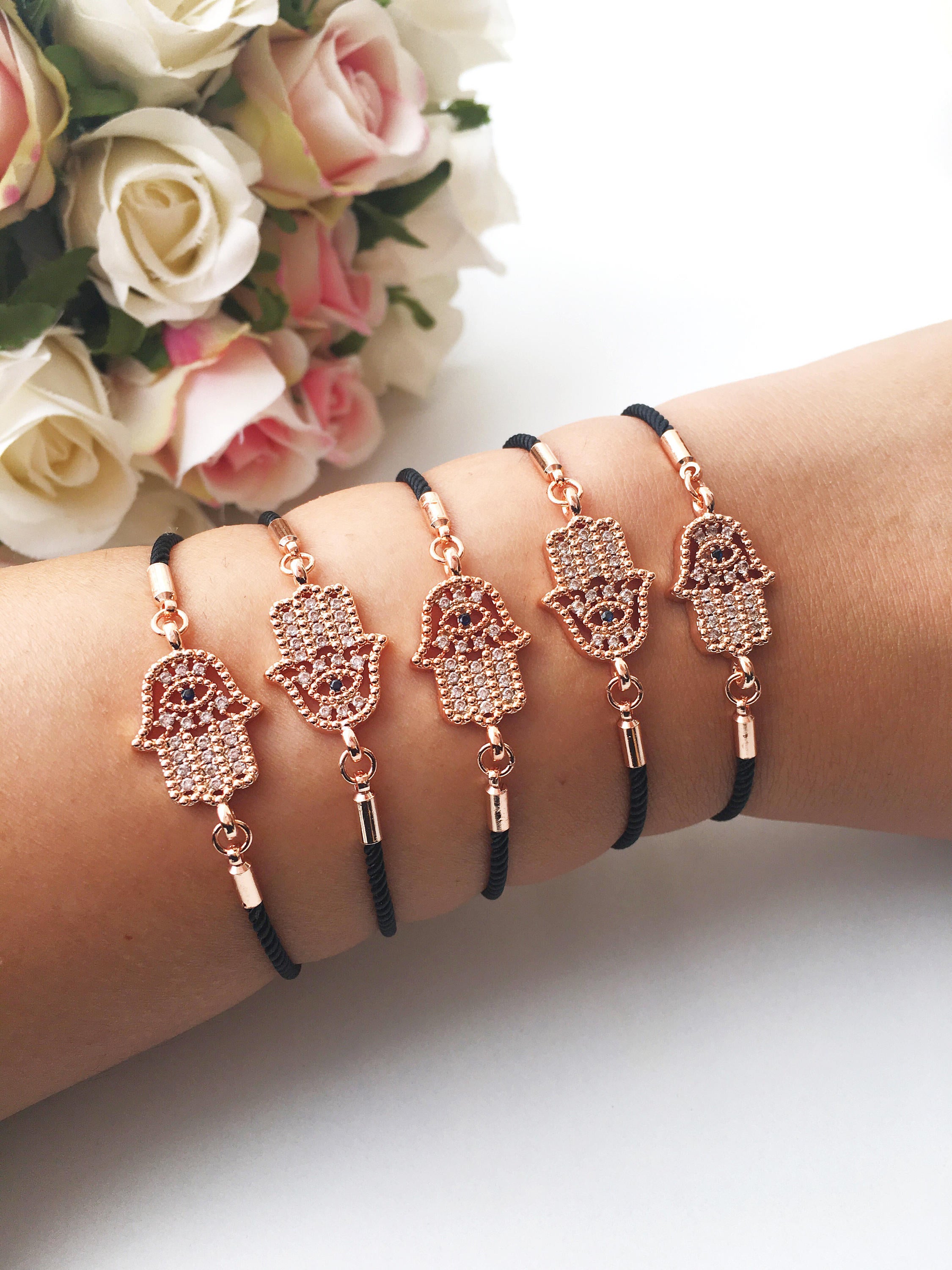 Handmade Hamsa charm bracelet featuring a rose gold zirconia charm on a black adjustable string.