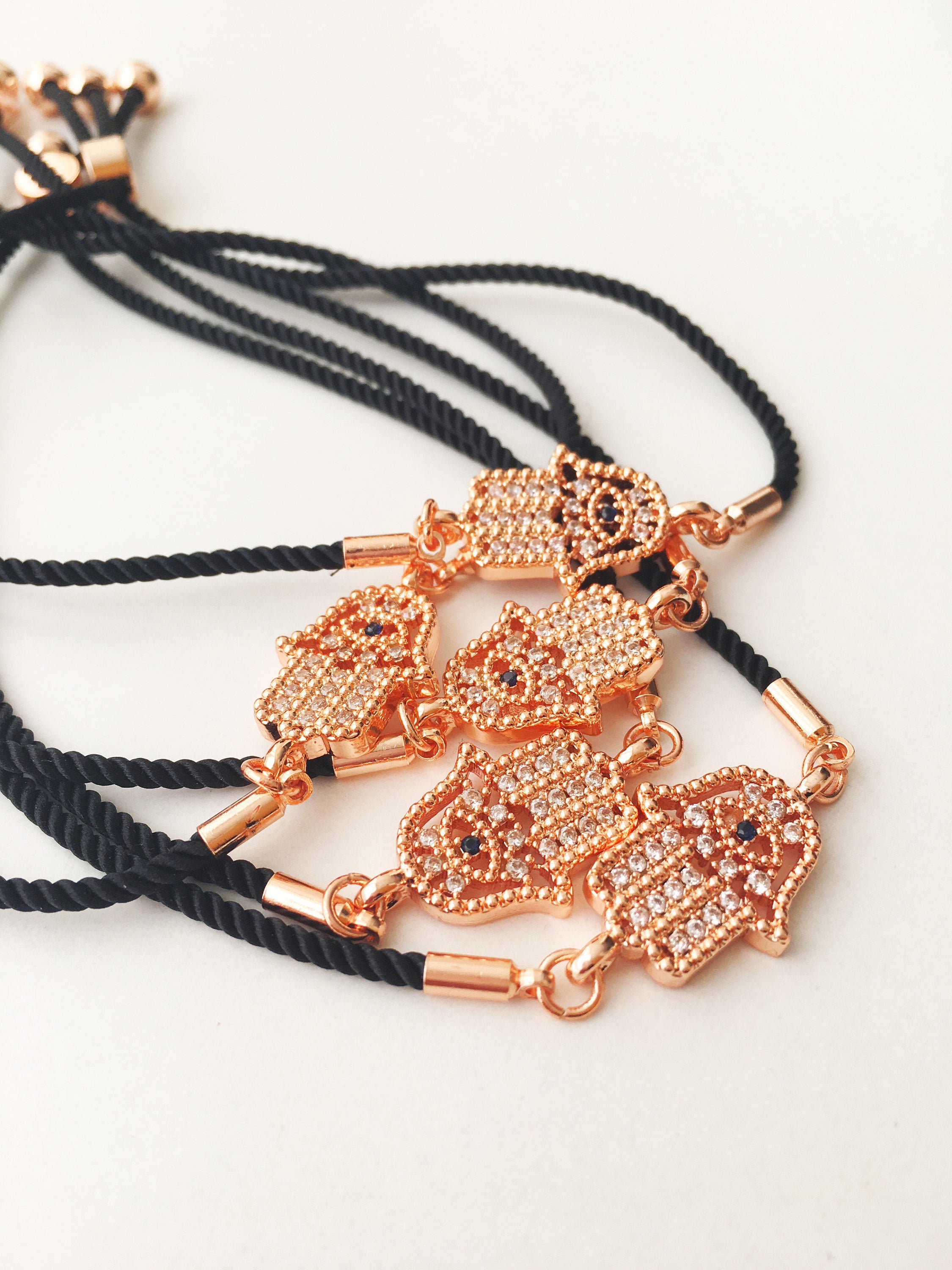 Handmade Hamsa charm bracelet featuring a rose gold zirconia charm on a black adjustable string.