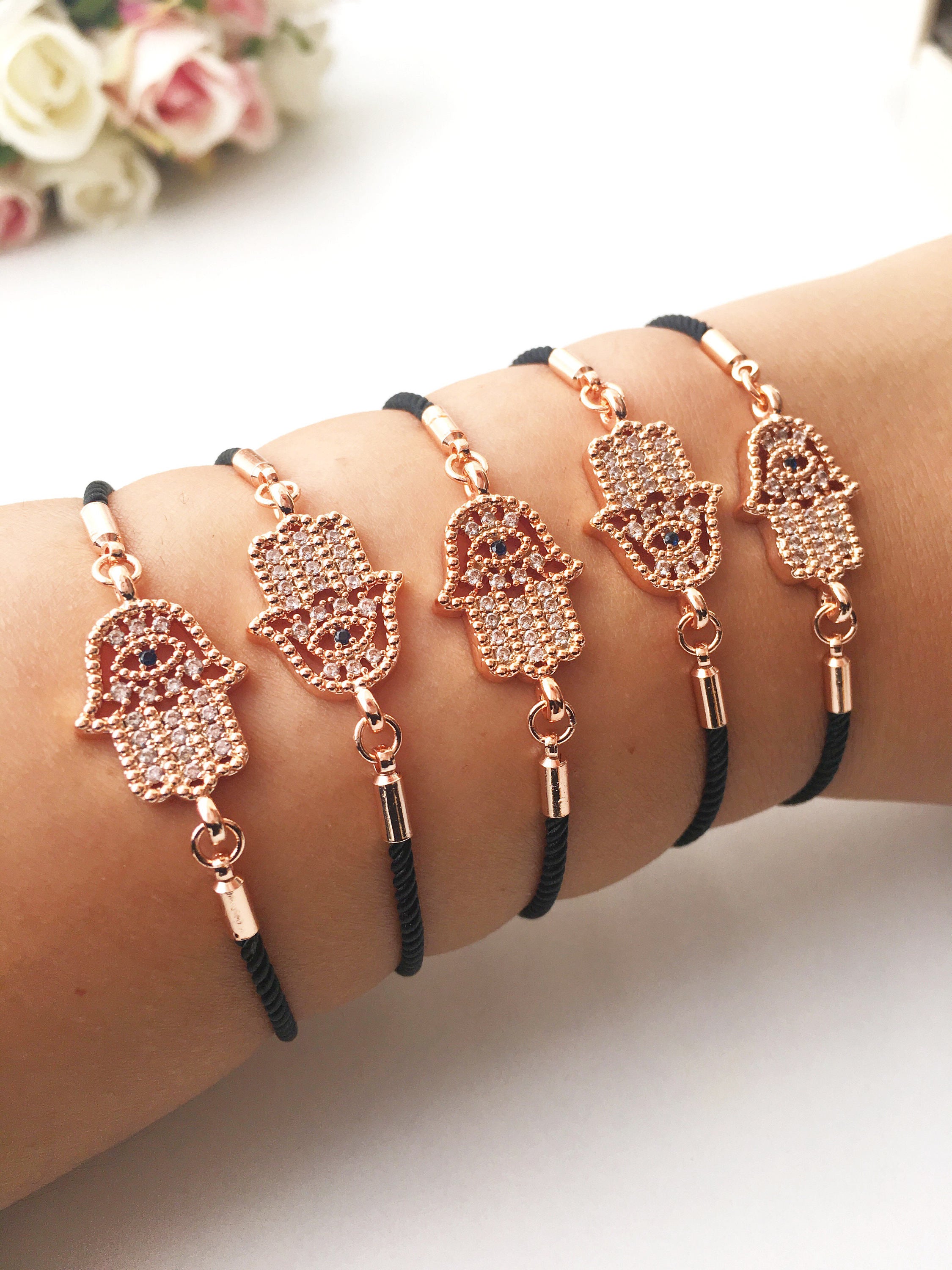 Handmade Hamsa charm bracelet featuring a rose gold zirconia charm on a black adjustable string.