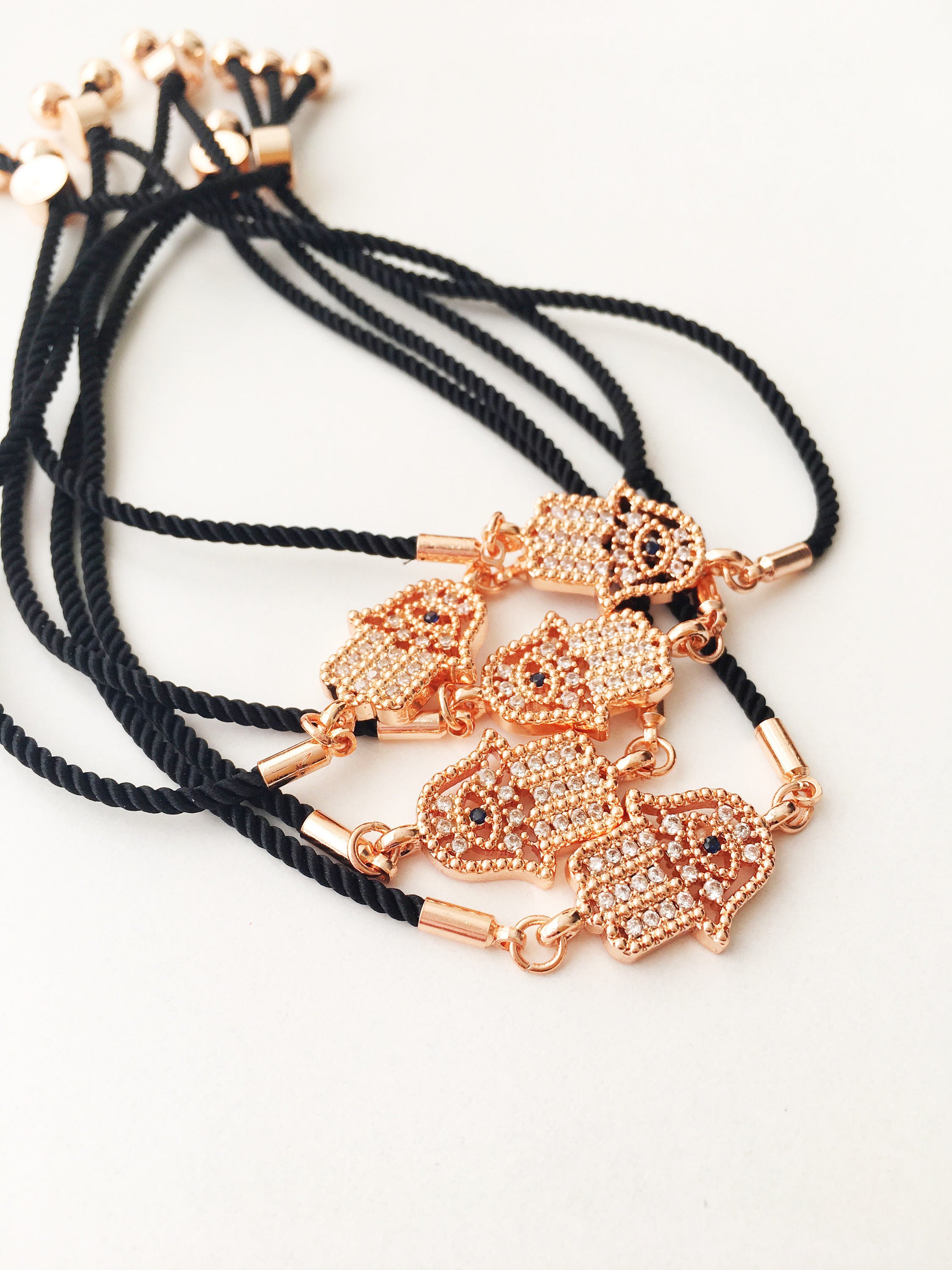 Handmade Hamsa charm bracelet featuring a rose gold zirconia charm on a black adjustable string.