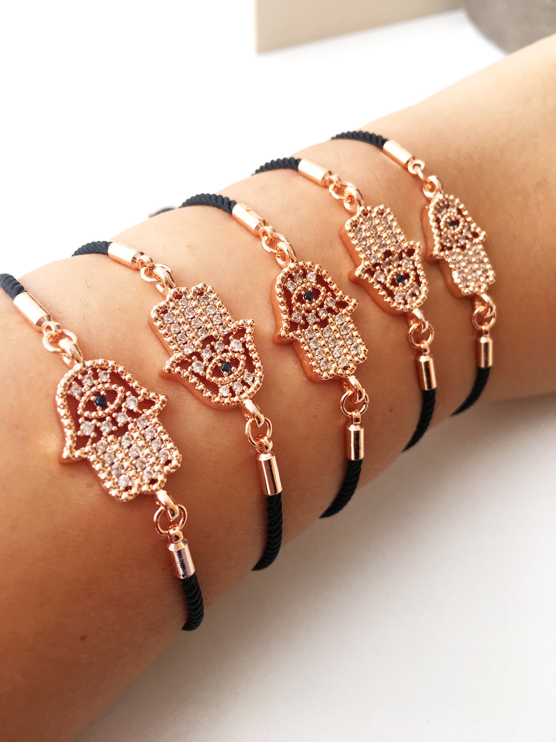 Handmade Hamsa charm bracelet featuring a rose gold zirconia charm on a black adjustable string.