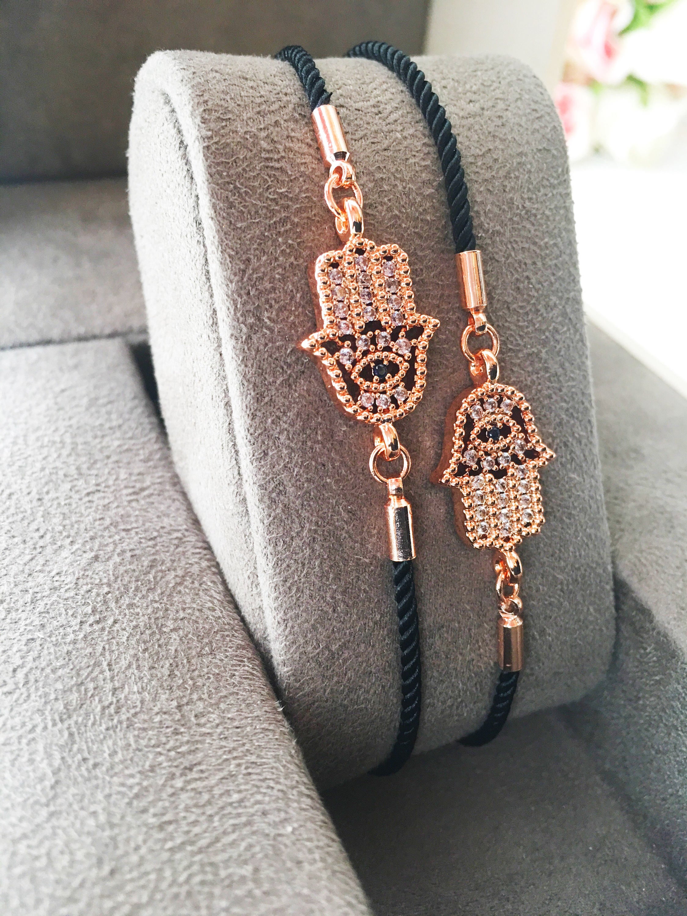 Handmade Hamsa charm bracelet featuring a rose gold zirconia charm on a black adjustable string.