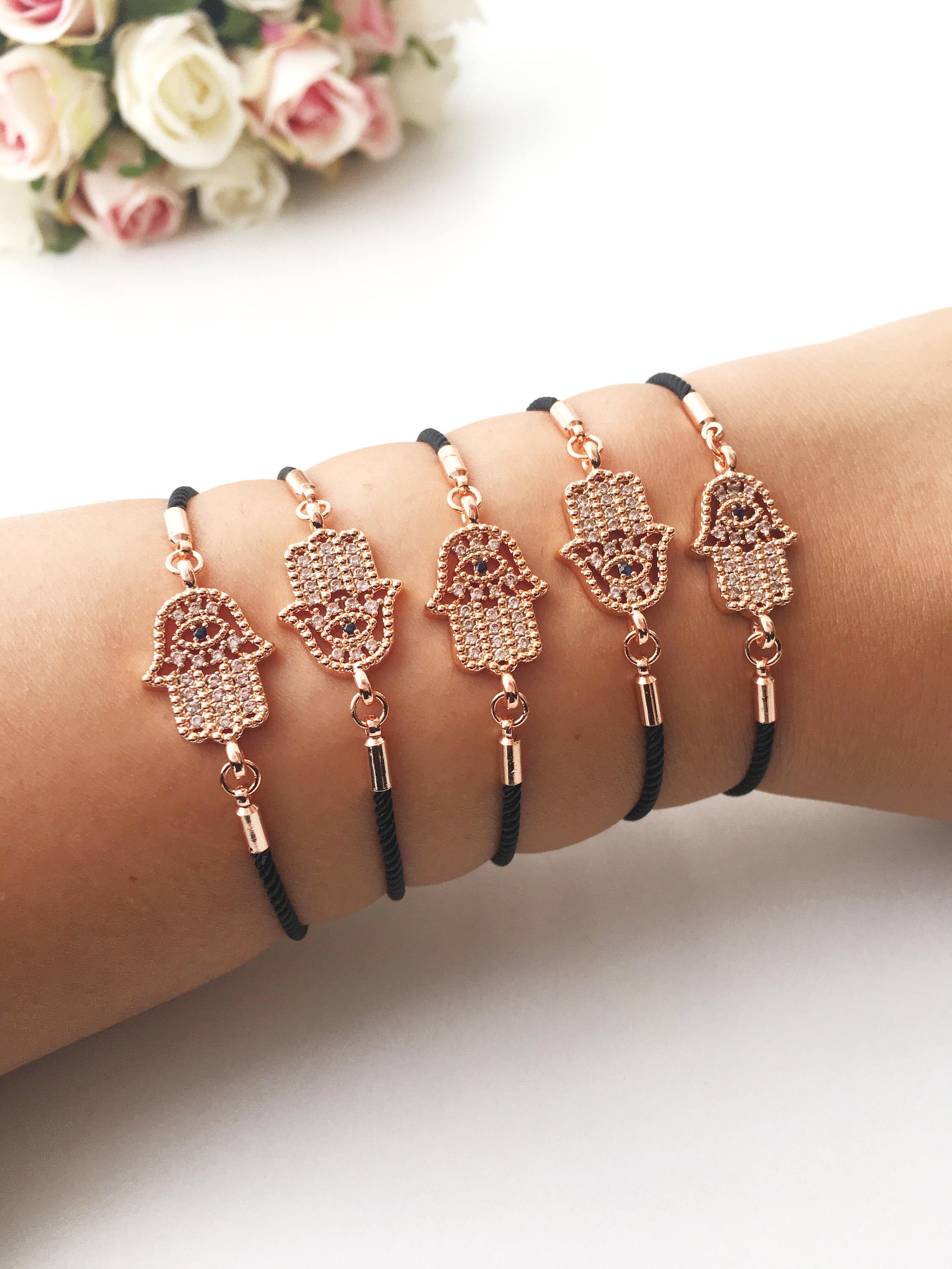 Handmade Hamsa charm bracelet featuring a rose gold zirconia charm on a black adjustable string.