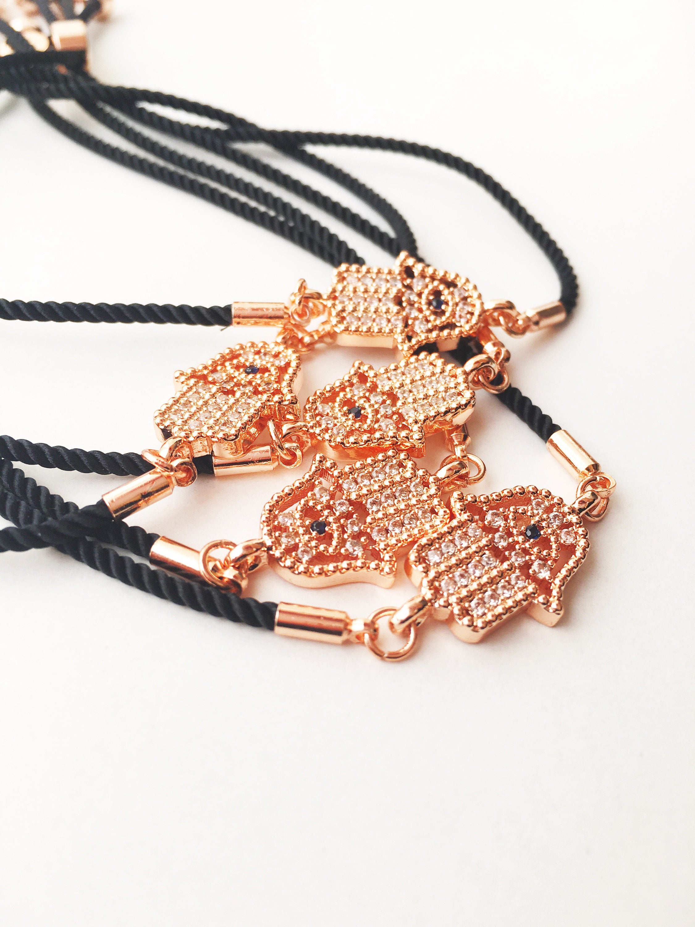 Handmade Hamsa charm bracelet featuring a rose gold zirconia charm on a black adjustable string.