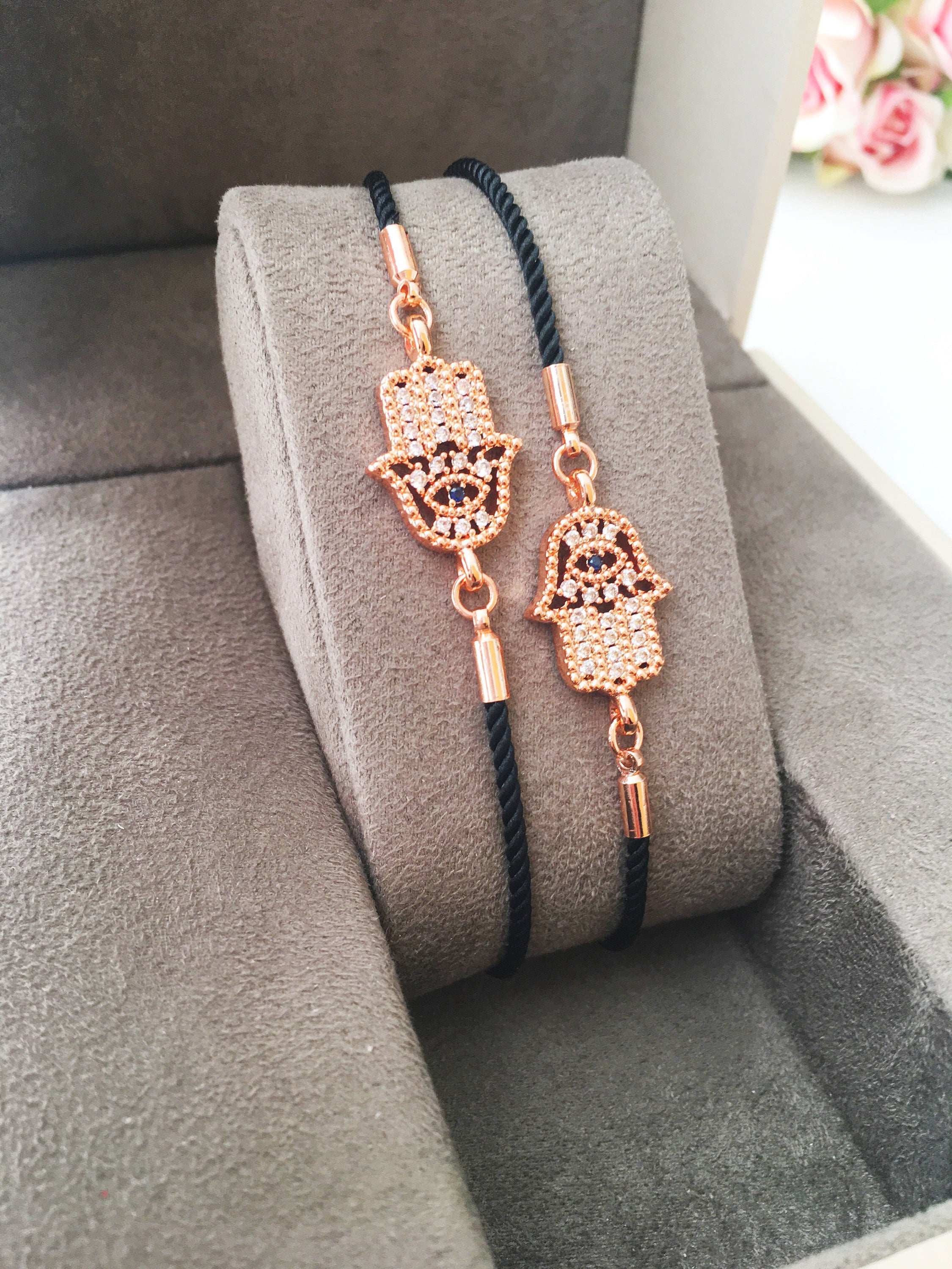 Handmade Hamsa charm bracelet featuring a rose gold zirconia charm on a black adjustable string.