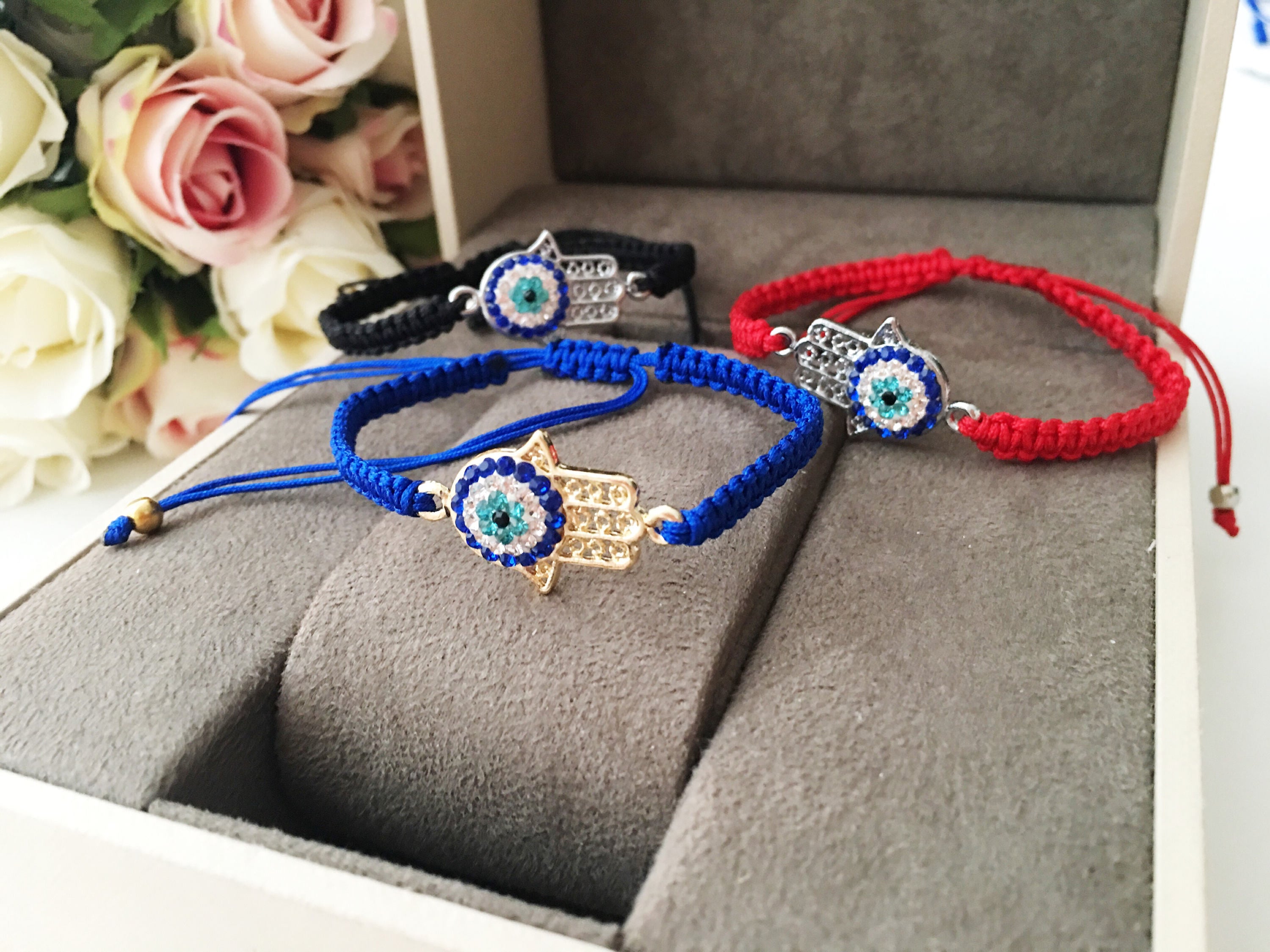 Handmade Hamsa Evil Eye Bracelet featuring silver or gold plating with adjustable macrame design and colorful string options.