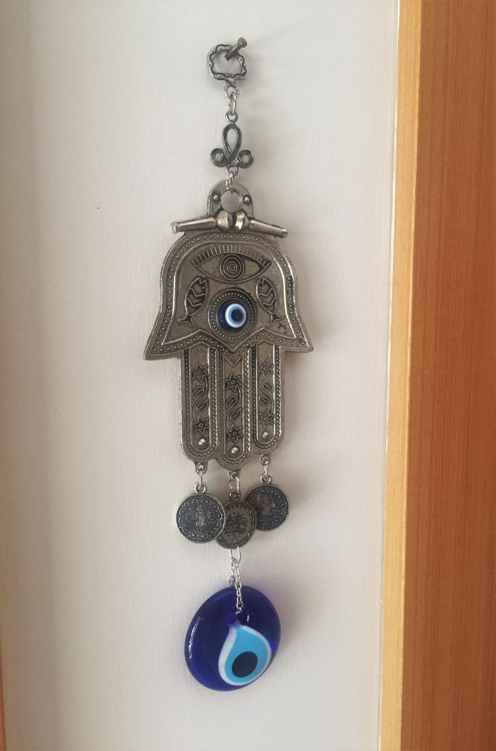 Hamsa wall art featuring a metal hand and large evil eye bead, symbolizing protection and good luck, beautifully crafted for home decor.