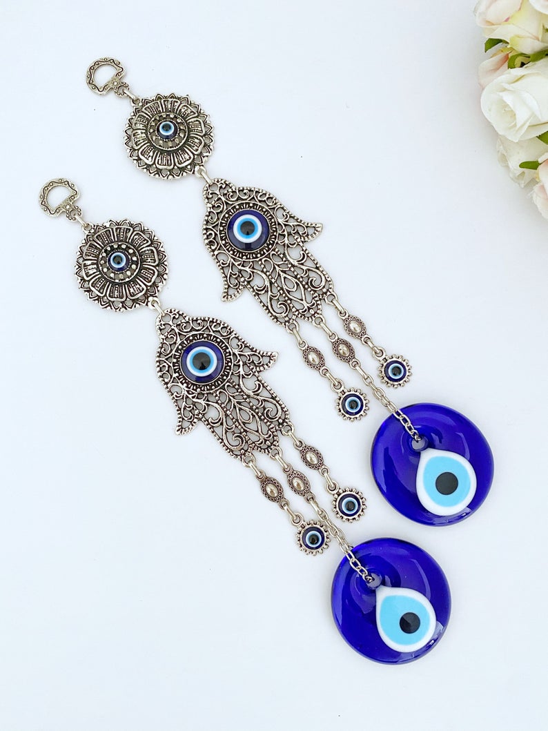 A beautifully crafted Hamsa wall decor featuring an evil eye design, made of metal with vibrant glass accents, perfect for home protection.