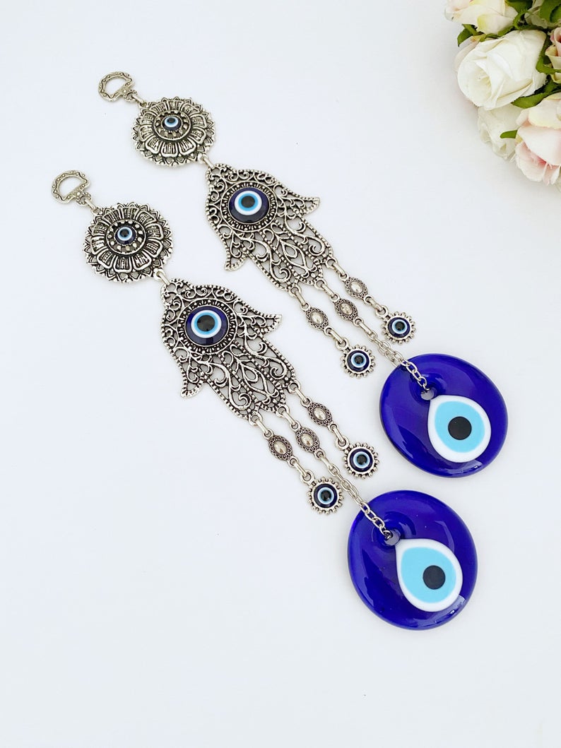 A beautifully crafted Hamsa wall decor featuring an evil eye design, made of metal with vibrant glass accents, perfect for home protection.