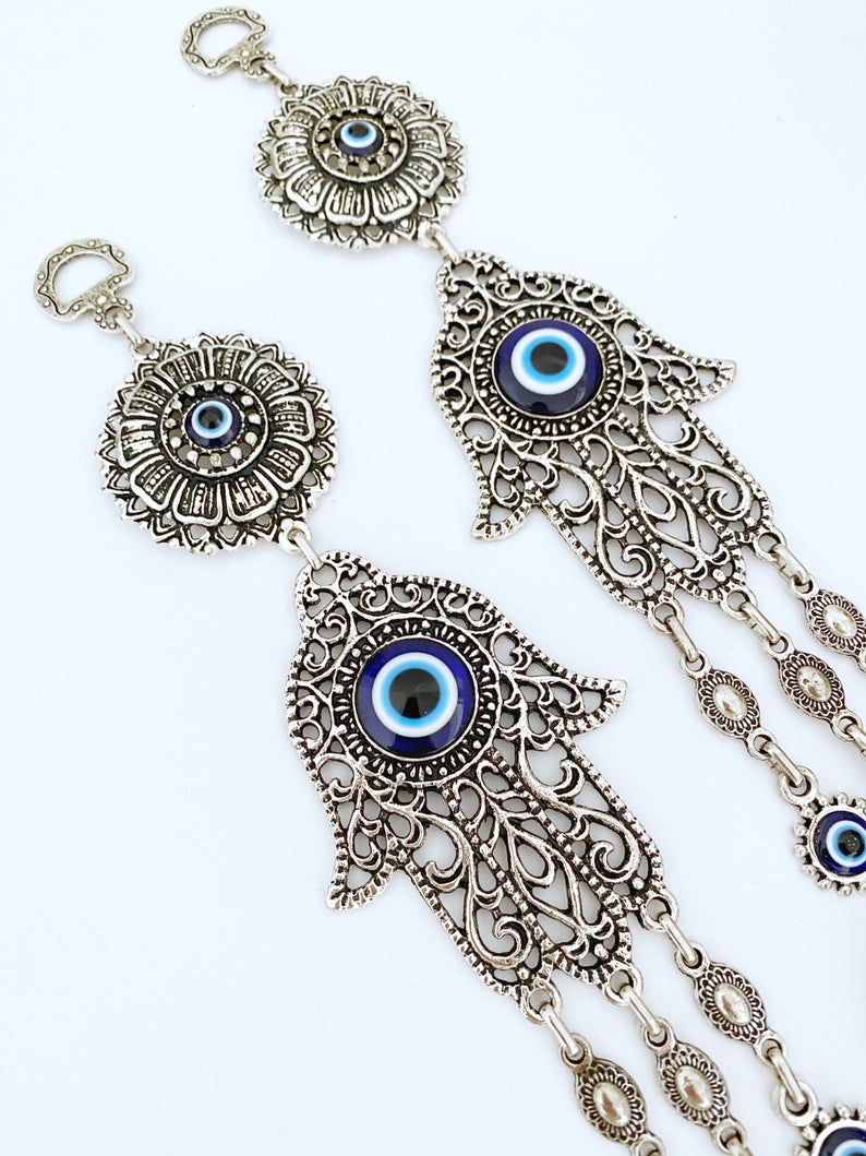 A beautifully crafted Hamsa wall decor featuring an evil eye design, made of metal with vibrant glass accents, perfect for home protection.