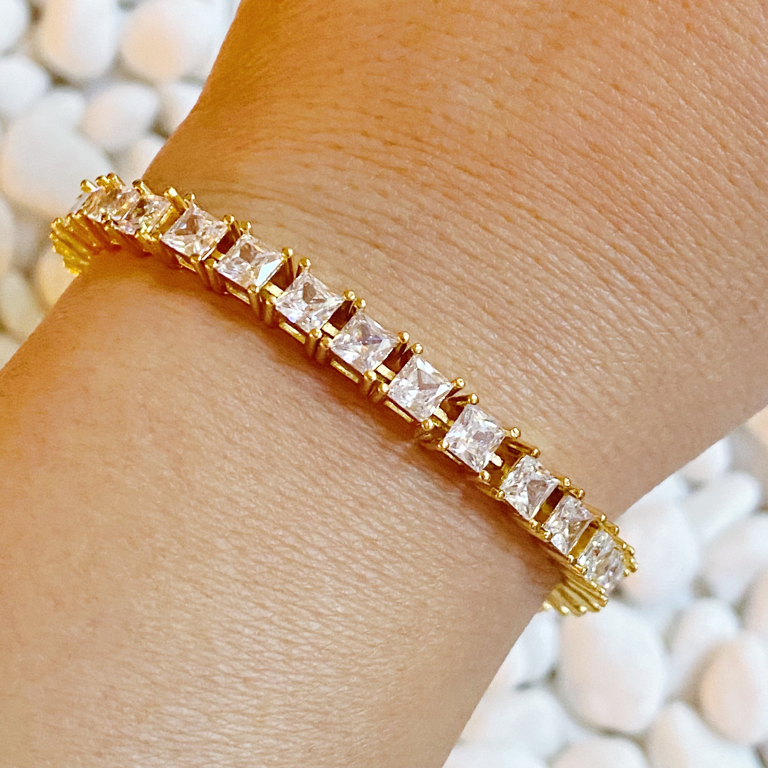 A stunning hand linked high class tennis bracelet featuring AAA grade Cubic Zirconia stones, gold plated brass, and a secure double closure.