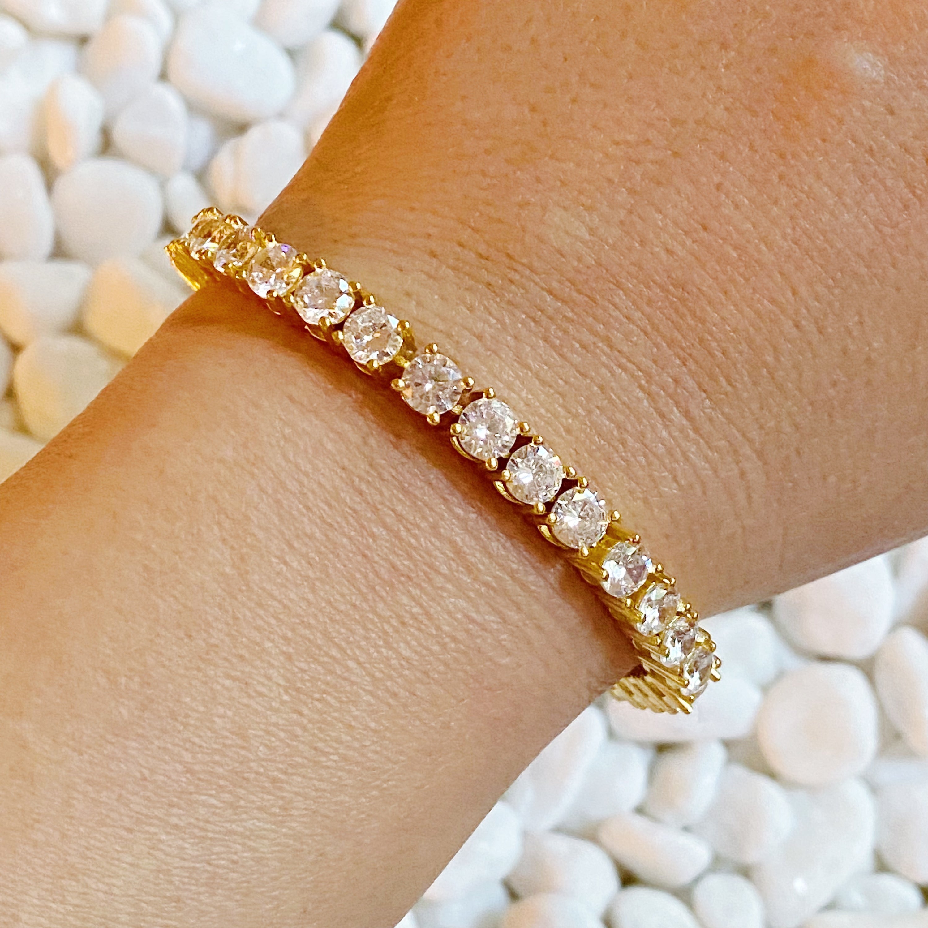 A stunning hand linked high class tennis bracelet featuring AAA grade Cubic Zirconia stones, gold plated brass, and a secure double closure.