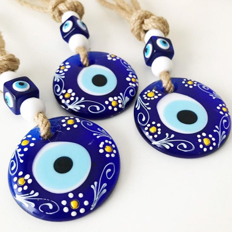 Hand-painted evil eye wall hanging featuring vibrant beads and intricate macrame design, symbolizing protection and good luck.