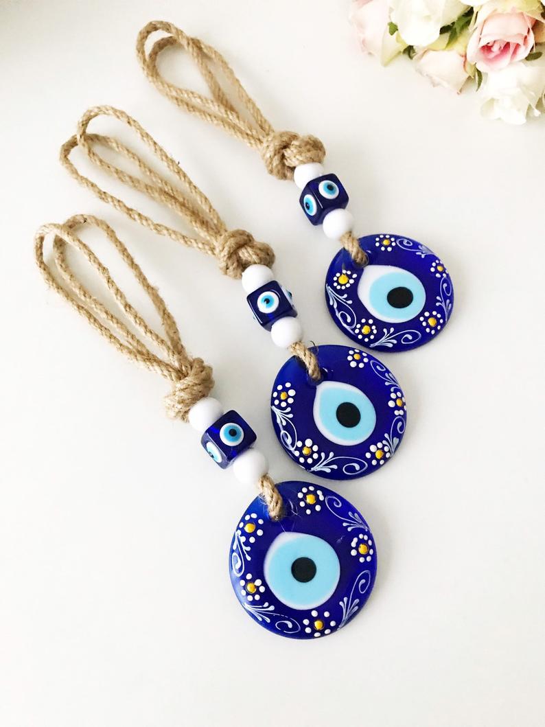 Hand-painted evil eye wall hanging featuring vibrant beads and intricate macrame design, symbolizing protection and good luck.