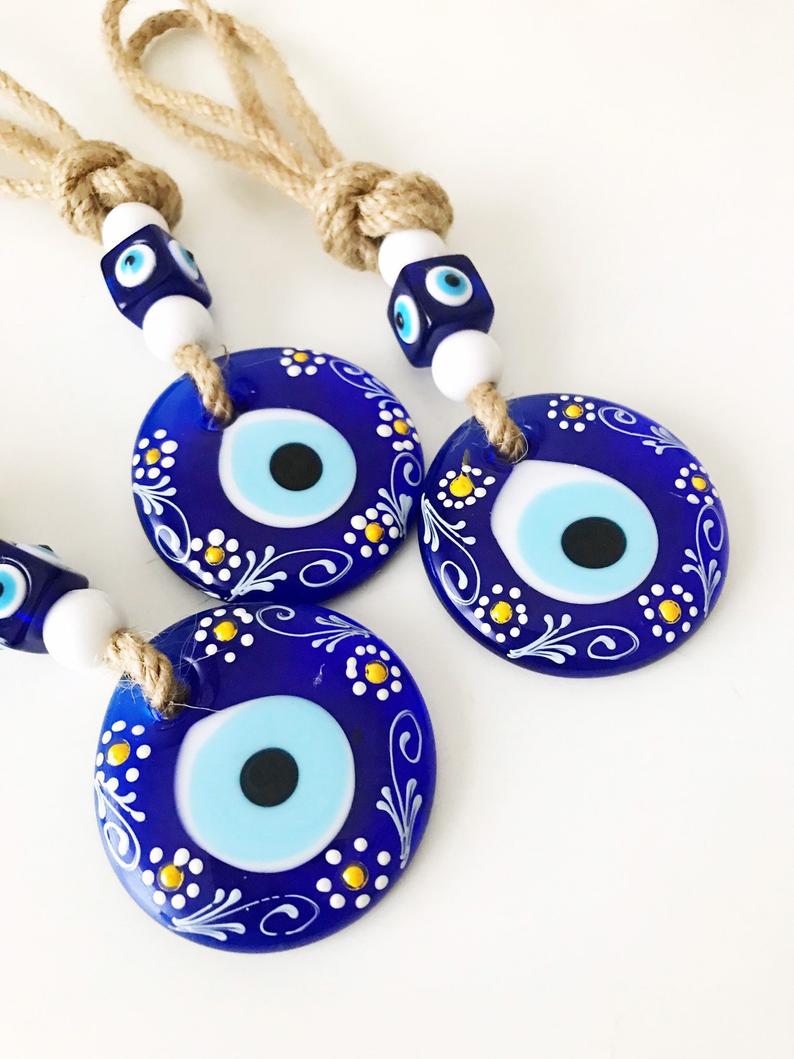 Hand-painted evil eye wall hanging featuring vibrant beads and intricate macrame design, symbolizing protection and good luck.