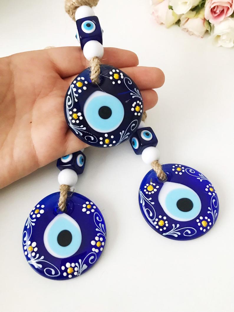 Hand-painted evil eye wall hanging featuring vibrant beads and intricate macrame design, symbolizing protection and good luck.