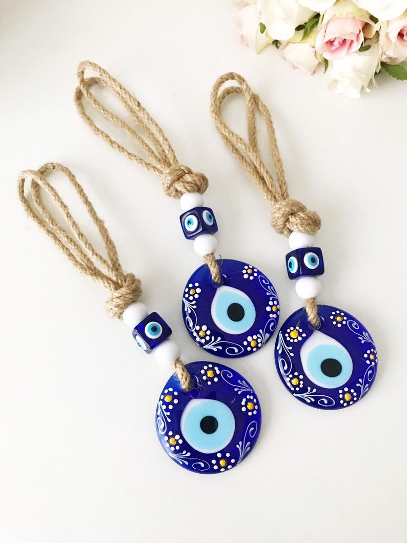 Hand-painted evil eye wall hanging featuring vibrant beads and intricate macrame design, symbolizing protection and good luck.