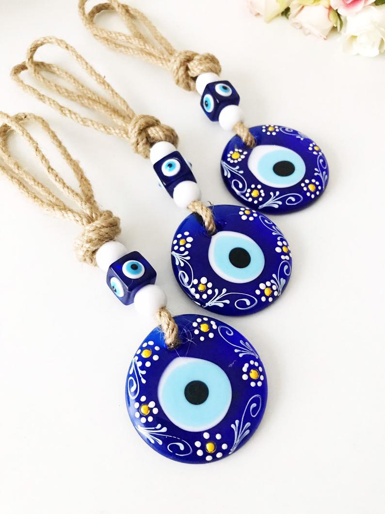 Hand-painted evil eye wall hanging featuring vibrant beads and intricate macrame design, symbolizing protection and good luck.