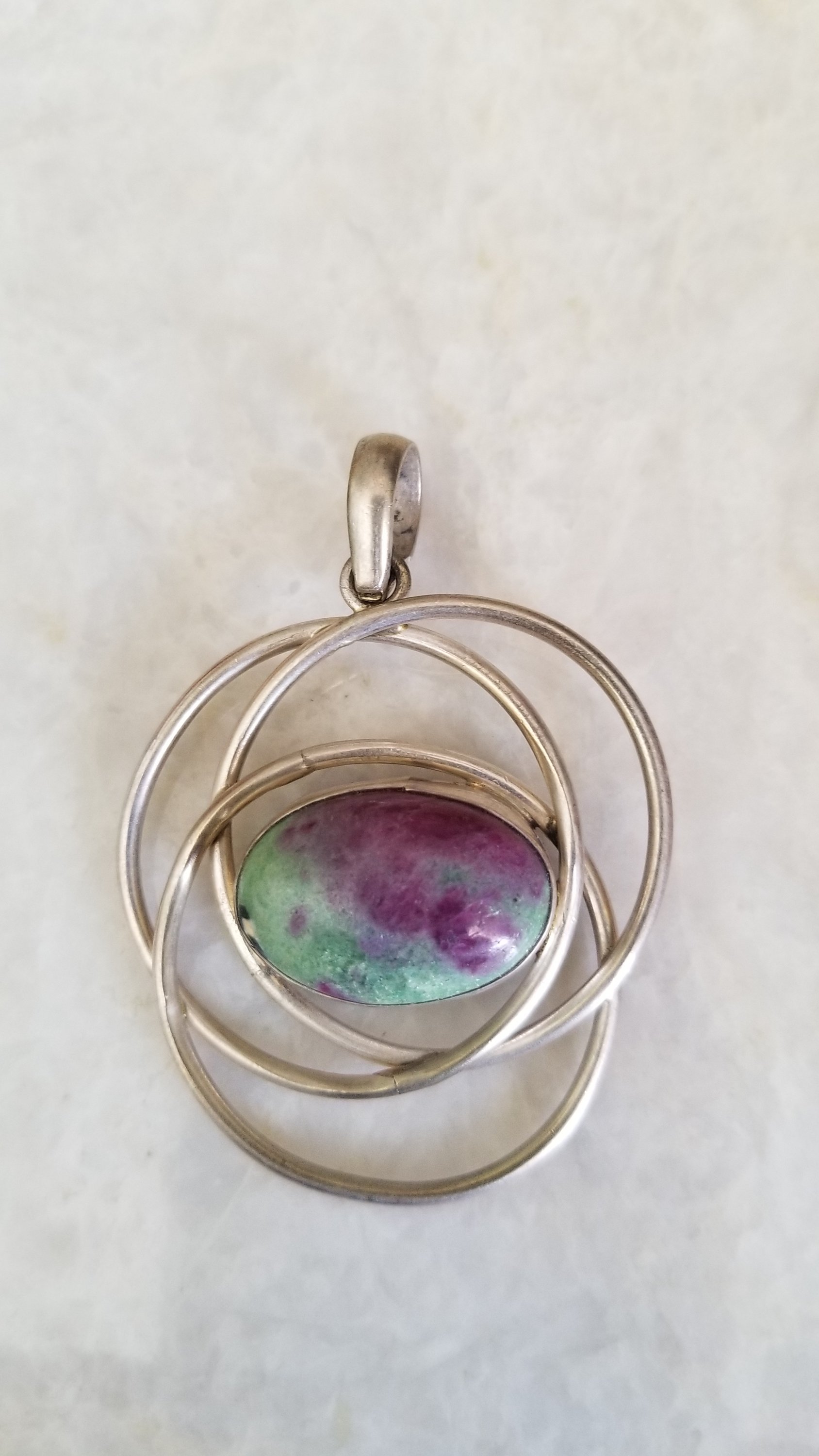 Hand wrapped silver pendant featuring natural Ruby Zoisite, showcasing vibrant red and green colors, handcrafted by Indian artisans.